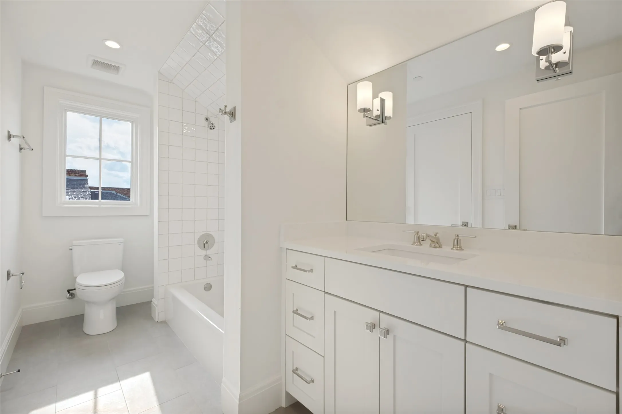 Spacious Jack and Jill bathroom featuring a functional tub/shower combination and generous counter space.