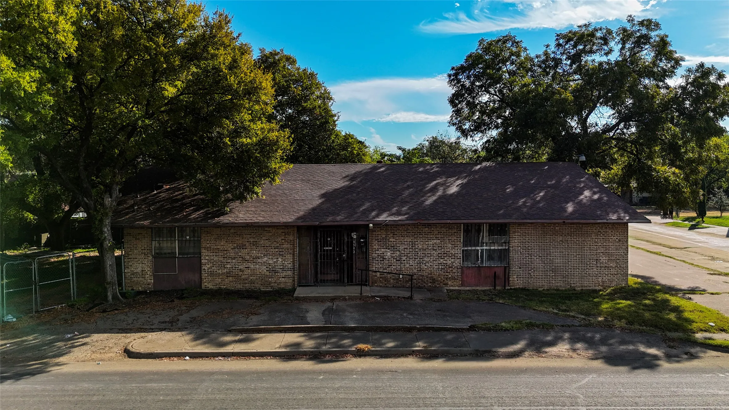 Brick exterior with a dark shingle roof and mature trees