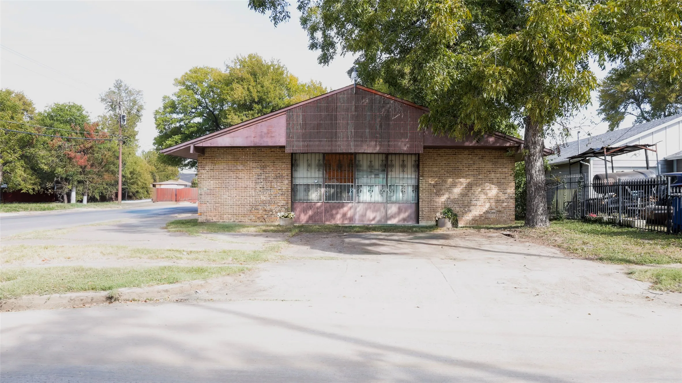 Brick facade with a sloped roofline and mature trees