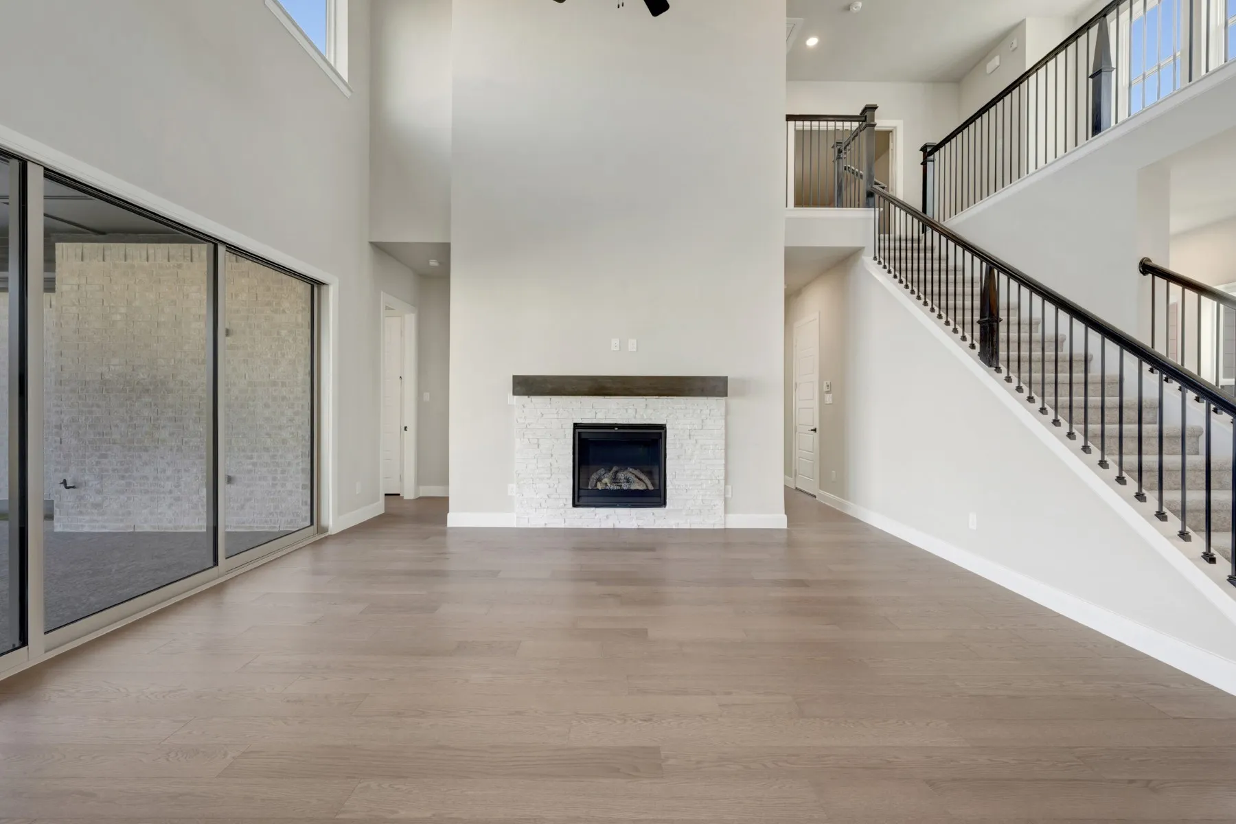 Unfurnished living room featuring light wood-style floors, a fireplace, a high ceiling, and recessed lighting