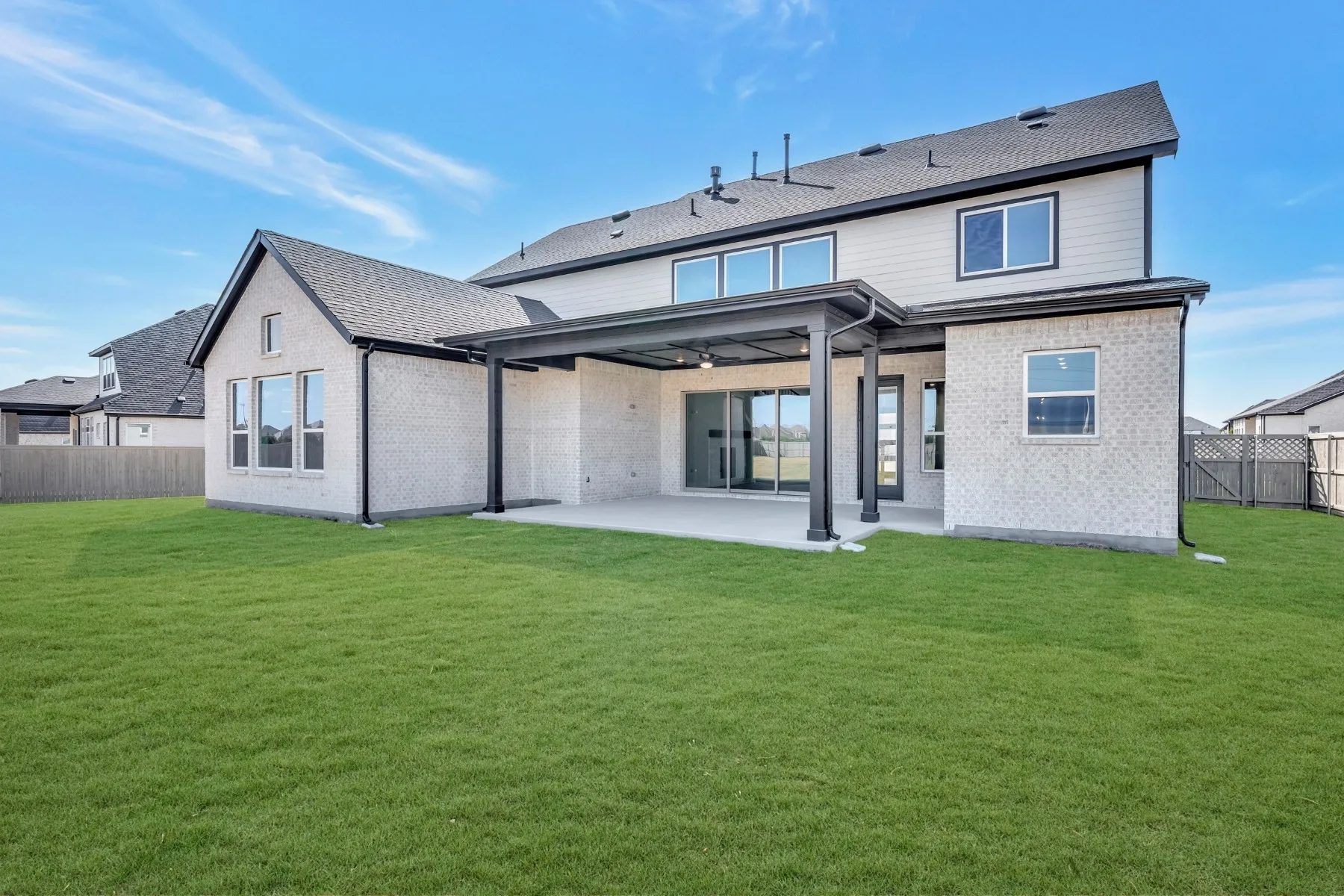 Back of house featuring a fenced backyard, a patio area, brick siding, and roof with shingles