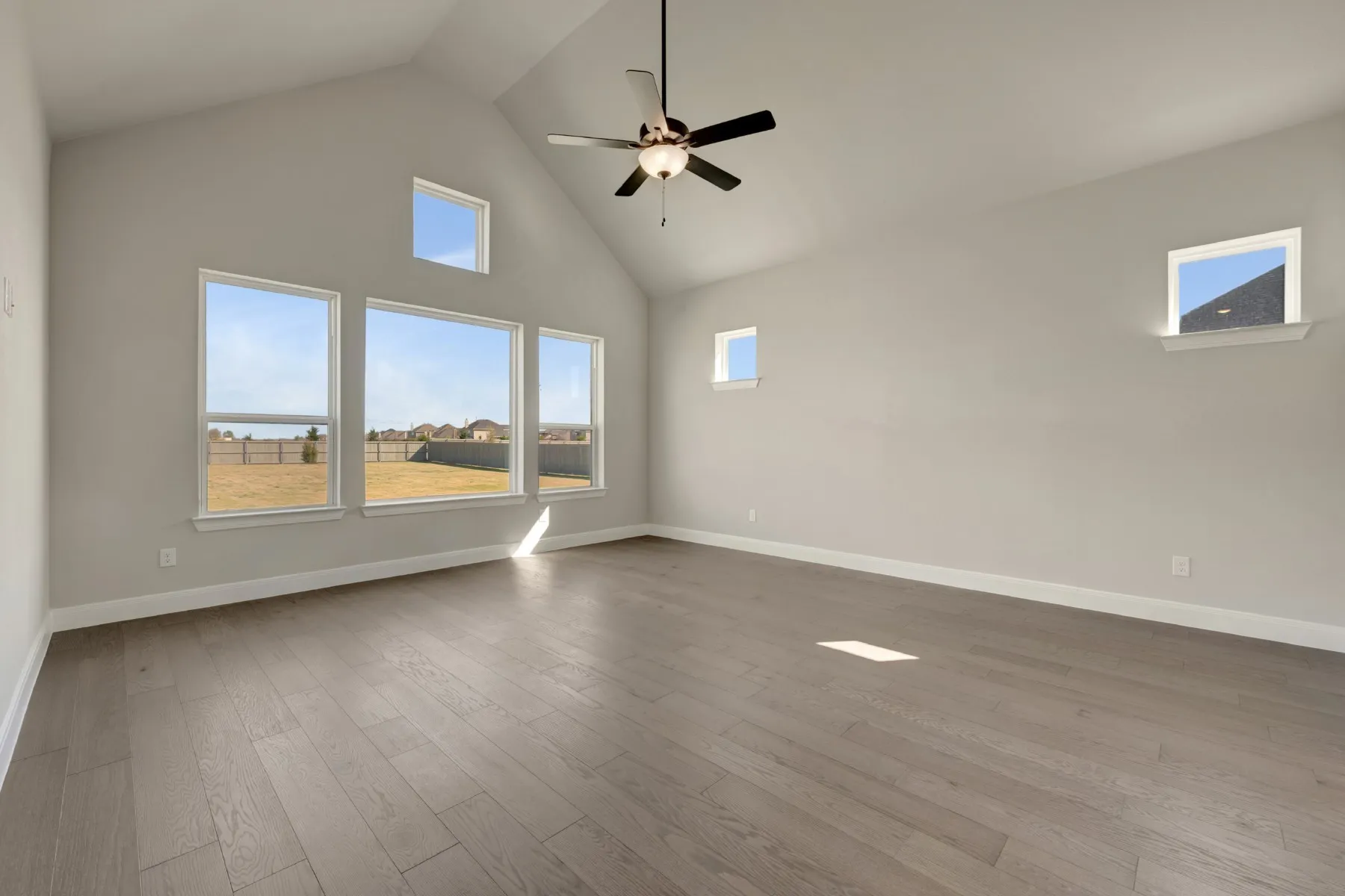 Empty room featuring a high ceiling, a ceiling fan, and dark wood finished floors