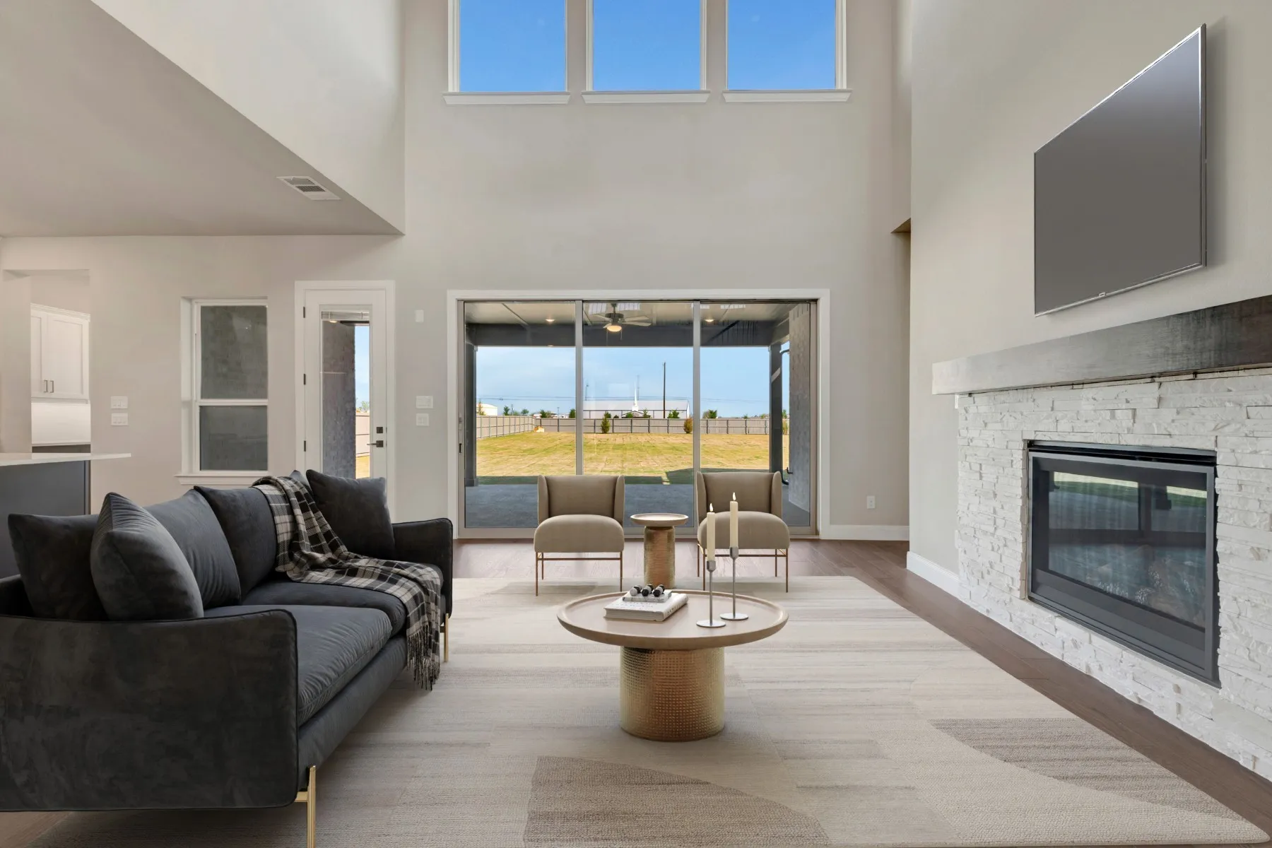 Living room with a fireplace, light wood-type flooring, and a high ceiling