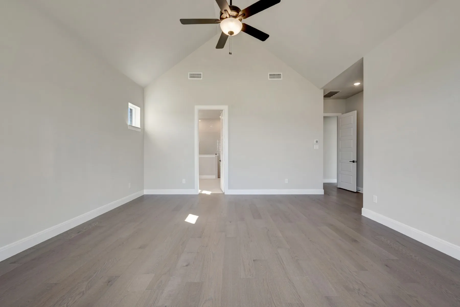 Unfurnished living room featuring dark wood-style flooring, vaulted ceiling, and ceiling fan