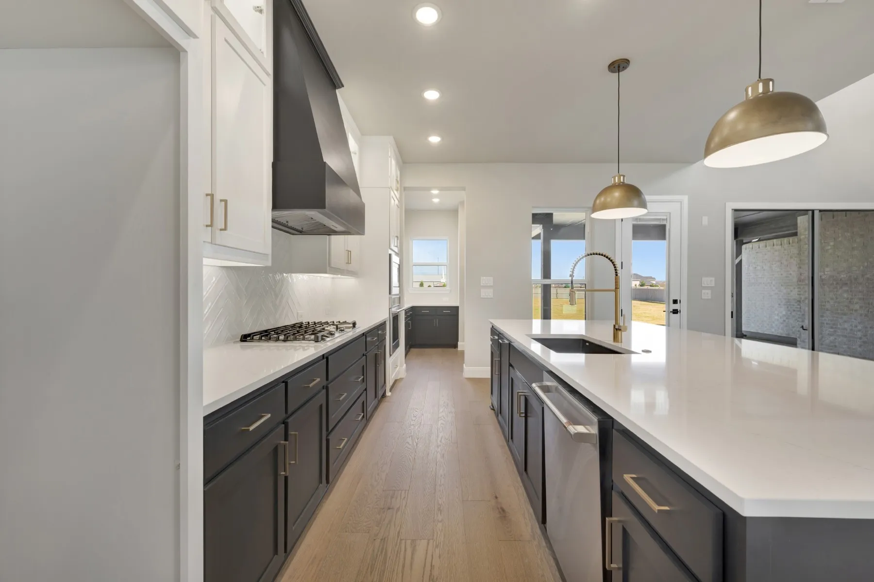 Kitchen with dual tone cabinetry, light wood-style floors, decorative light fixtures, a large island, and stainless steel appliances