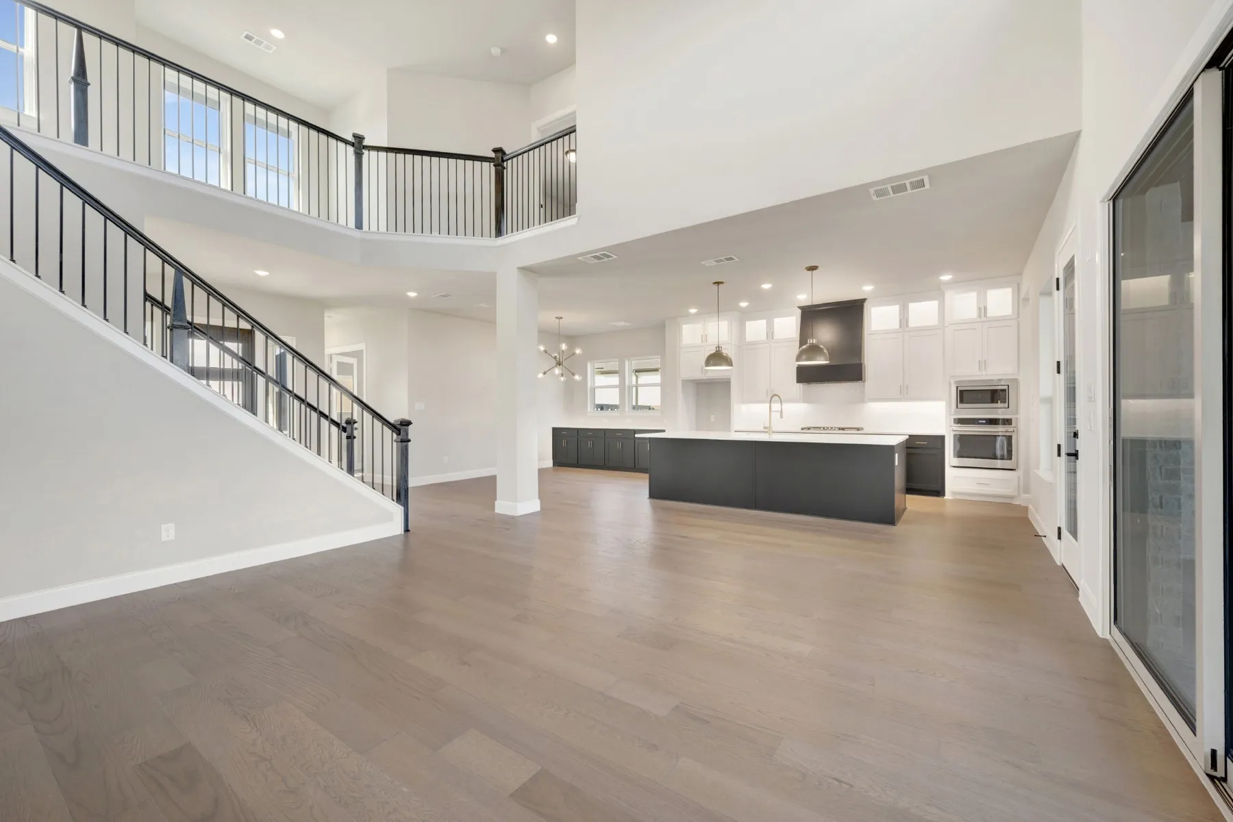 Unfurnished living room with light wood-style flooring, a chandelier, and a high ceiling