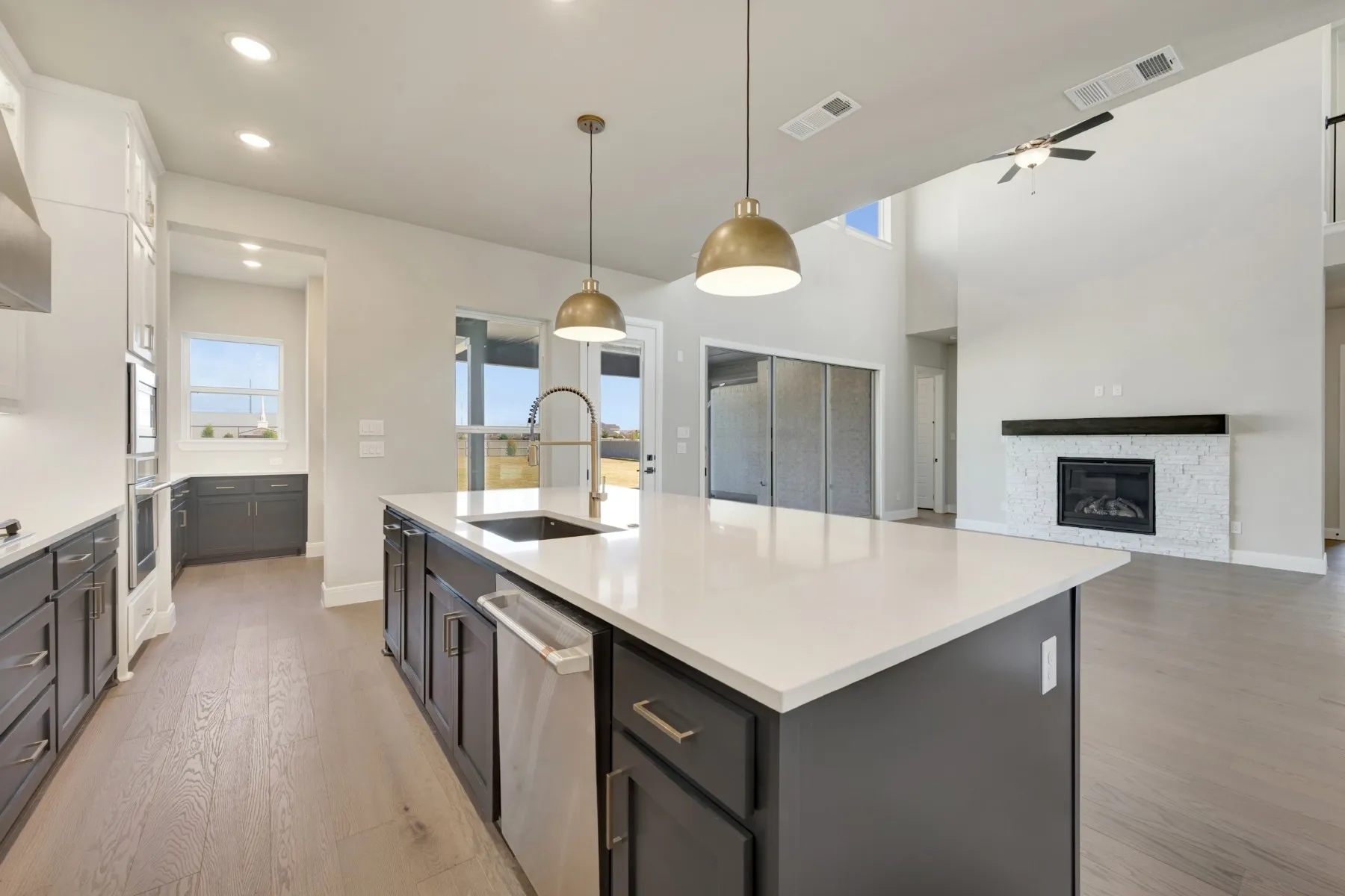 Dual tone kitchen featuring decorative light fixtures, light wood-type flooring, stainless steel appliances, healthy amount of natural light, and dual tone cabinetry