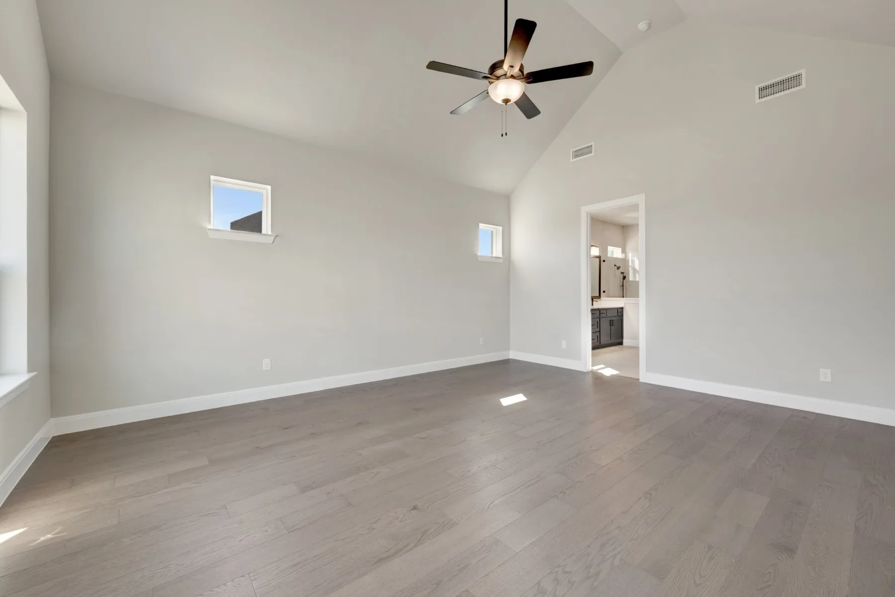 Spare room with ceiling fan, light wood finished floors, plenty of natural light, and vaulted ceiling