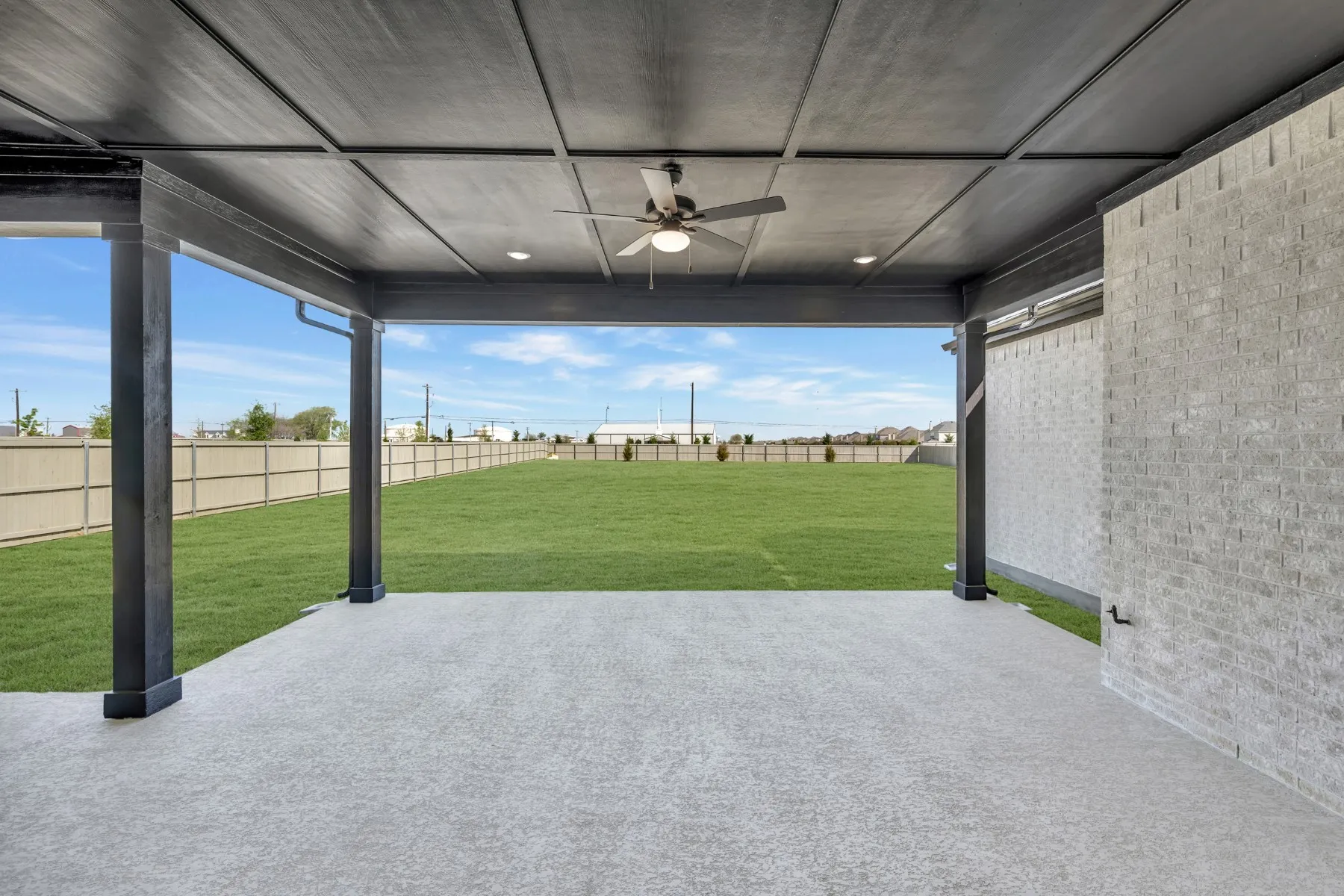 Fenced backyard featuring a ceiling fan and a patio