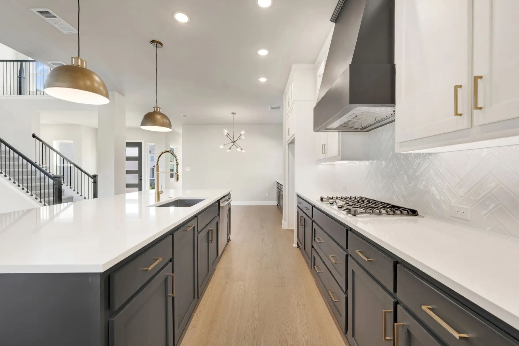 Two tone kitchen featuring light wood-style flooring, two tone cabinets, suspended lighting, a spacious island, and light stone counters