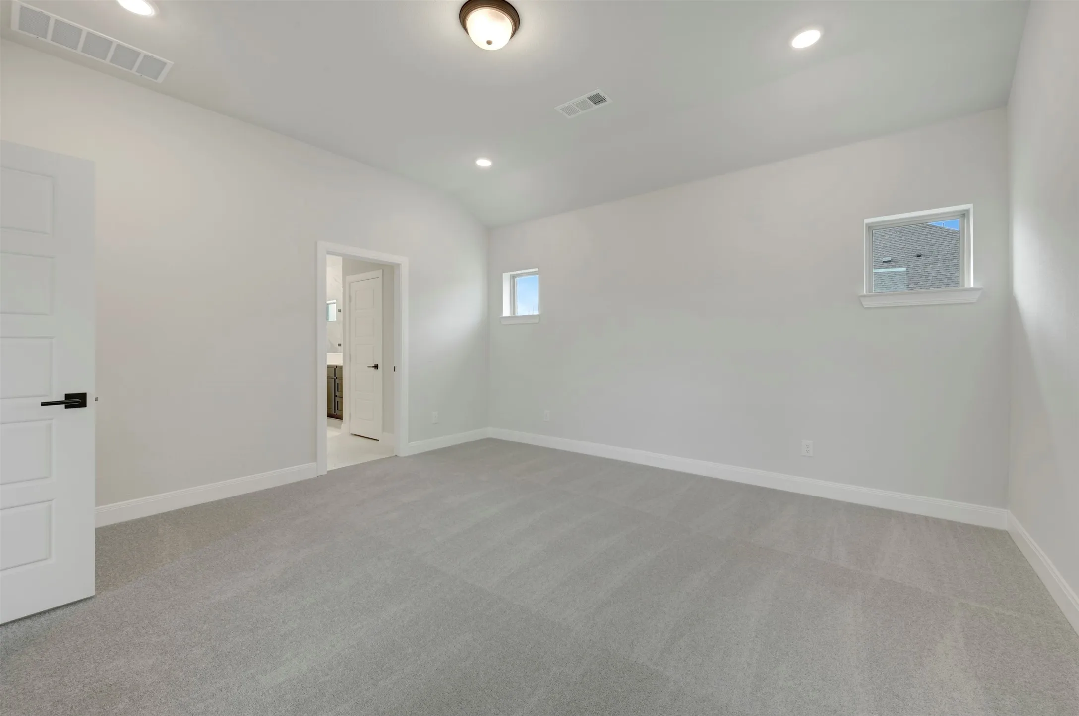 Empty room with light carpet, vaulted ceiling, and recessed lighting