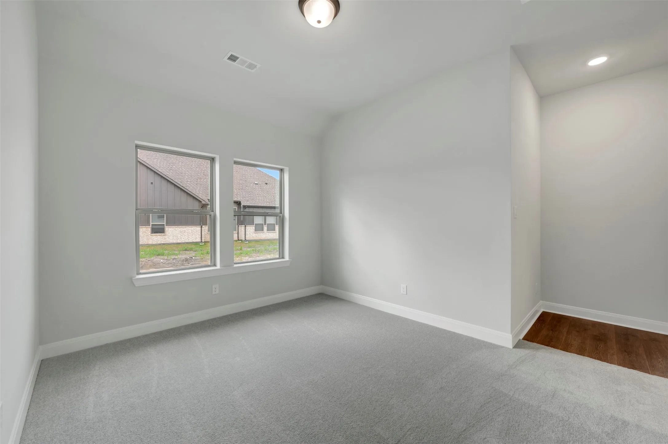 Unfurnished room featuring light carpet and lofted ceiling