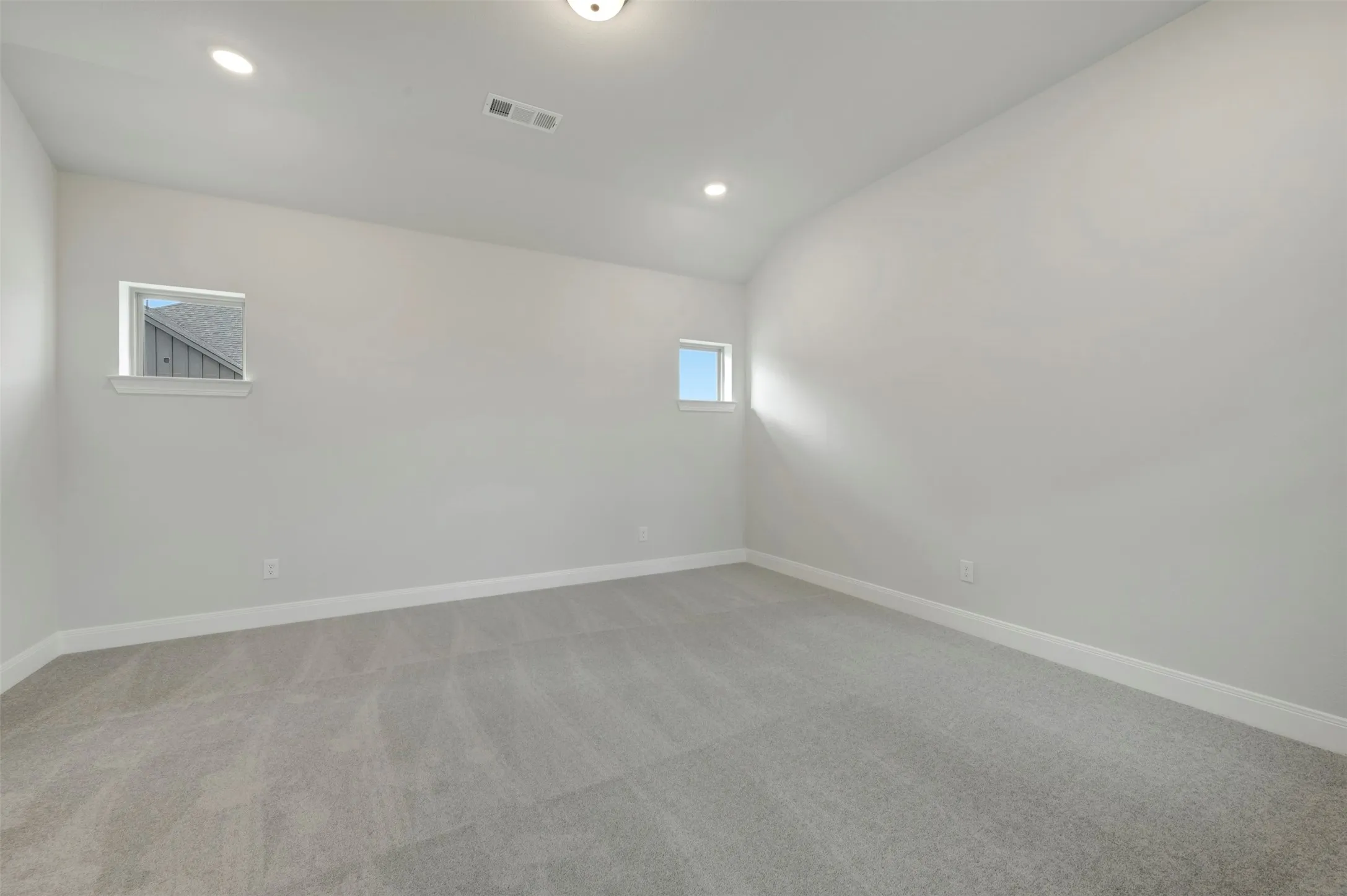 Spare room featuring light colored carpet, lofted ceiling, and recessed lighting
