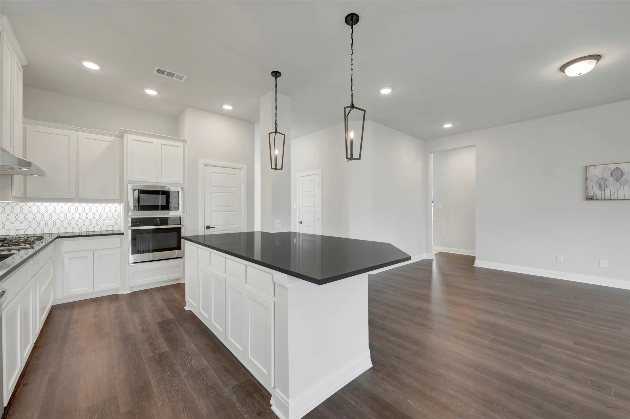 Kitchen with white cabinetry, stainless steel oven, decorative backsplash, and a center island