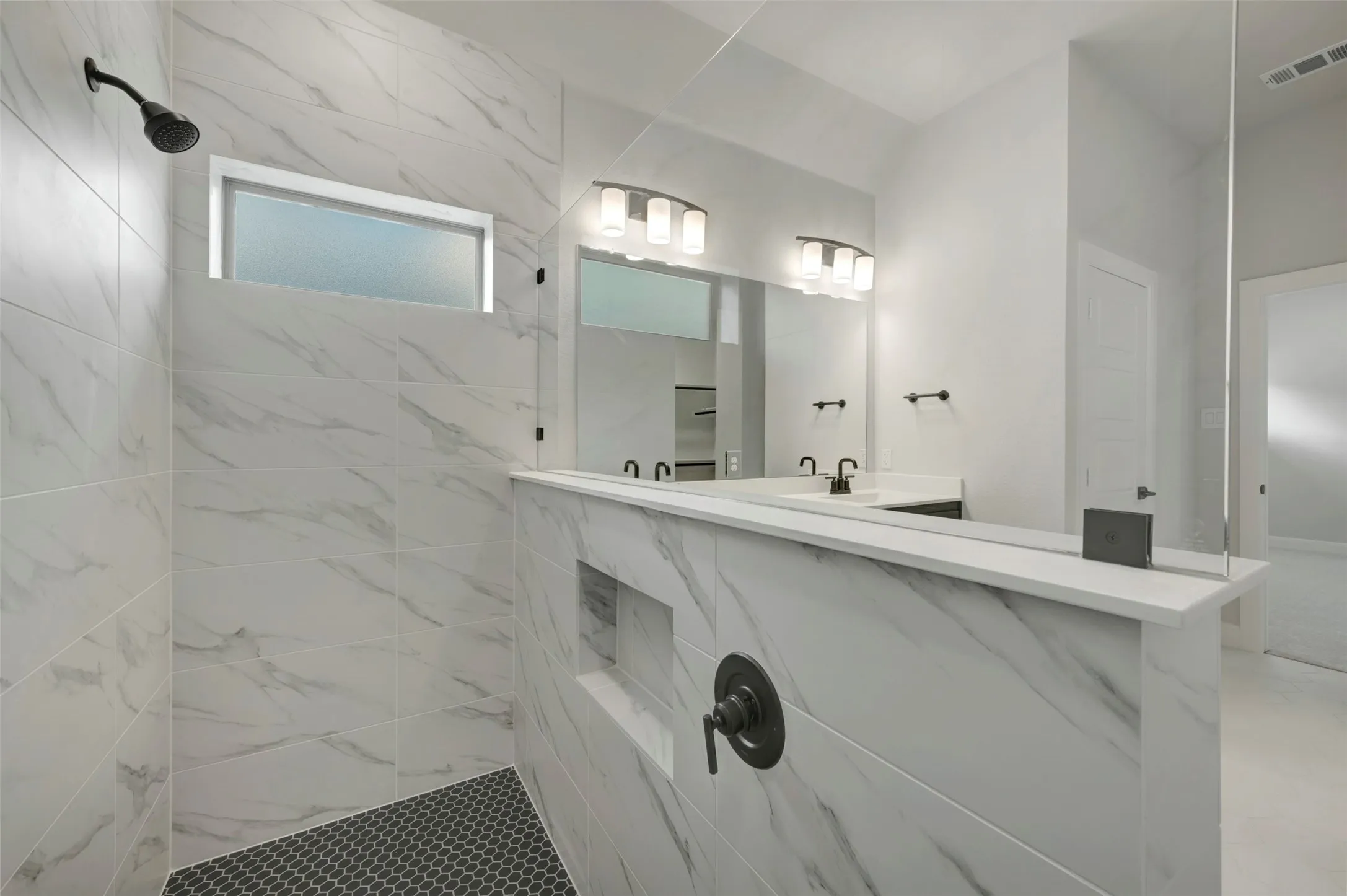 Bathroom featuring a marble finish shower and vanity