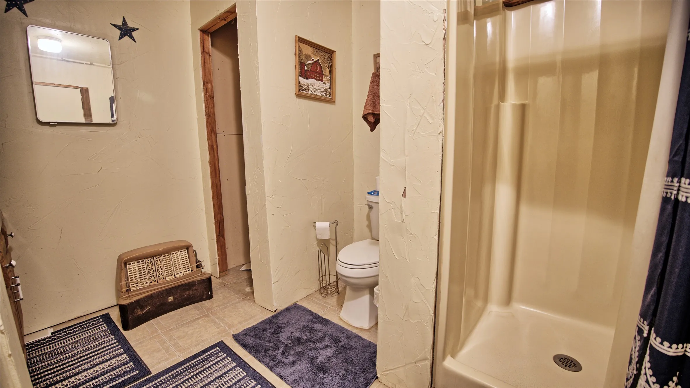 Full bathroom with a textured wall, a shower stall, and tile patterned flooring