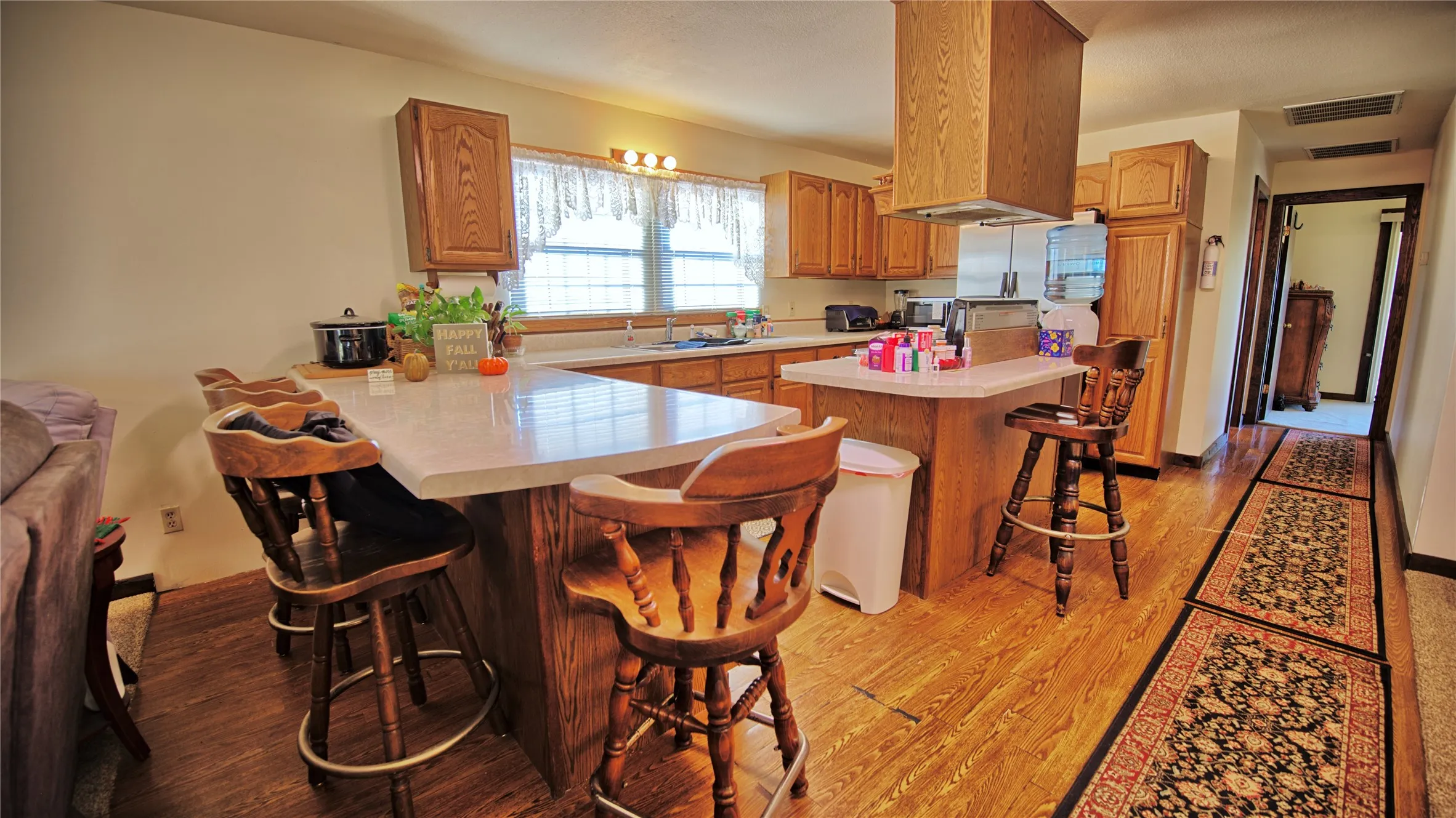 Kitchen featuring a kitchen breakfast bar, light countertops, a center island, light wood-style floors, and a peninsula