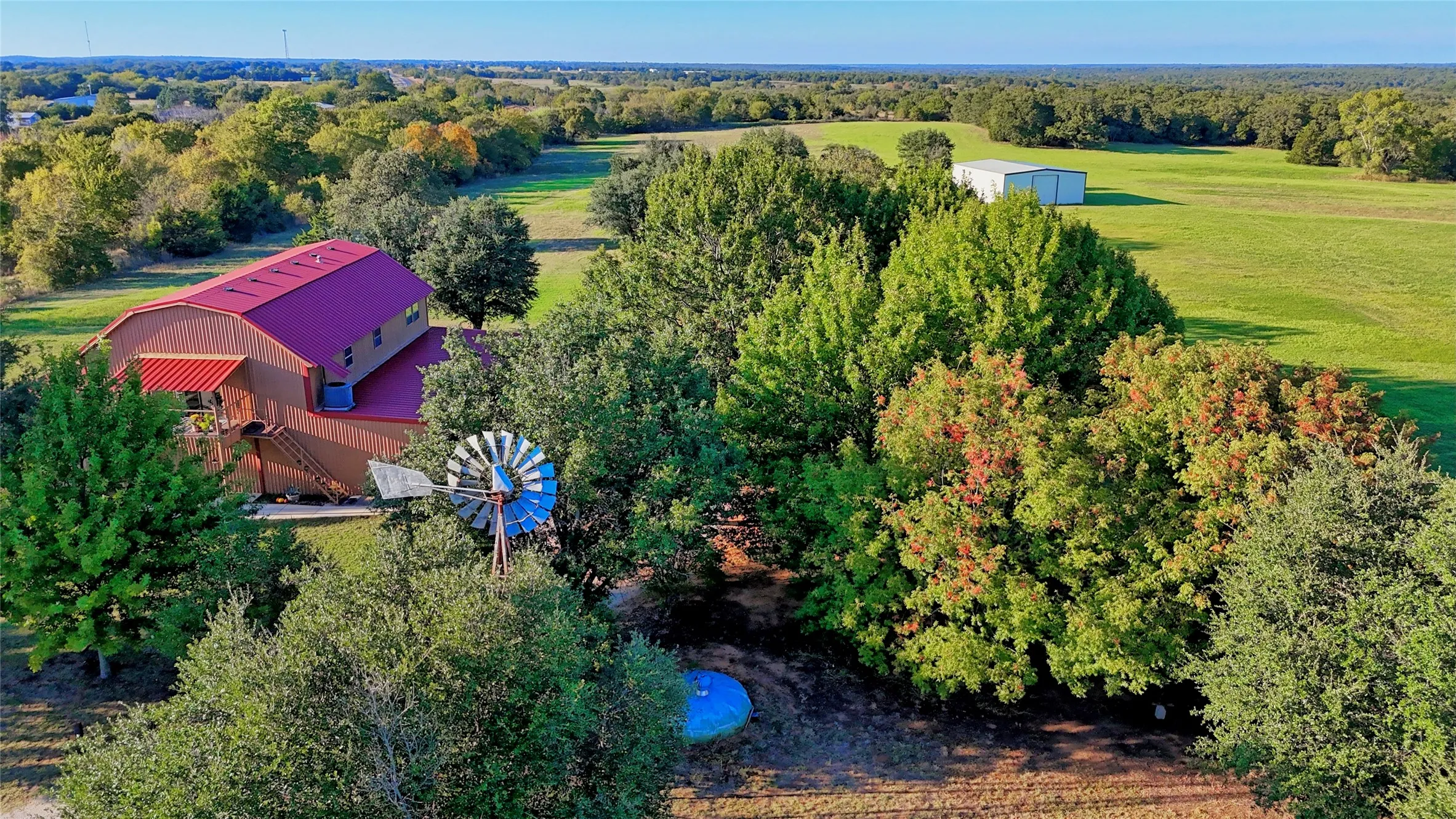 Aerial view of property and surrounding area featuring a forest