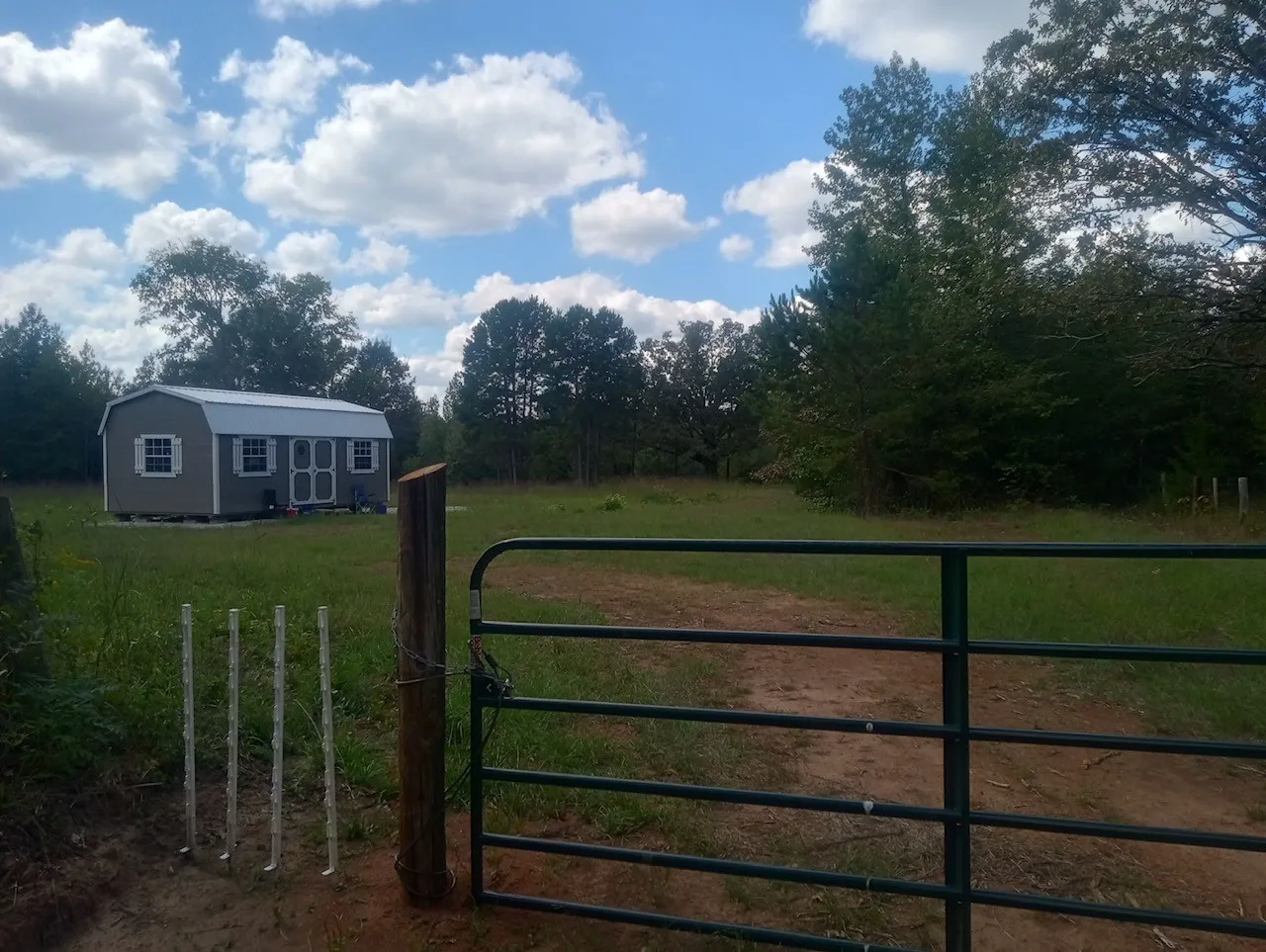 Gate with an outbuilding and view of wooded area