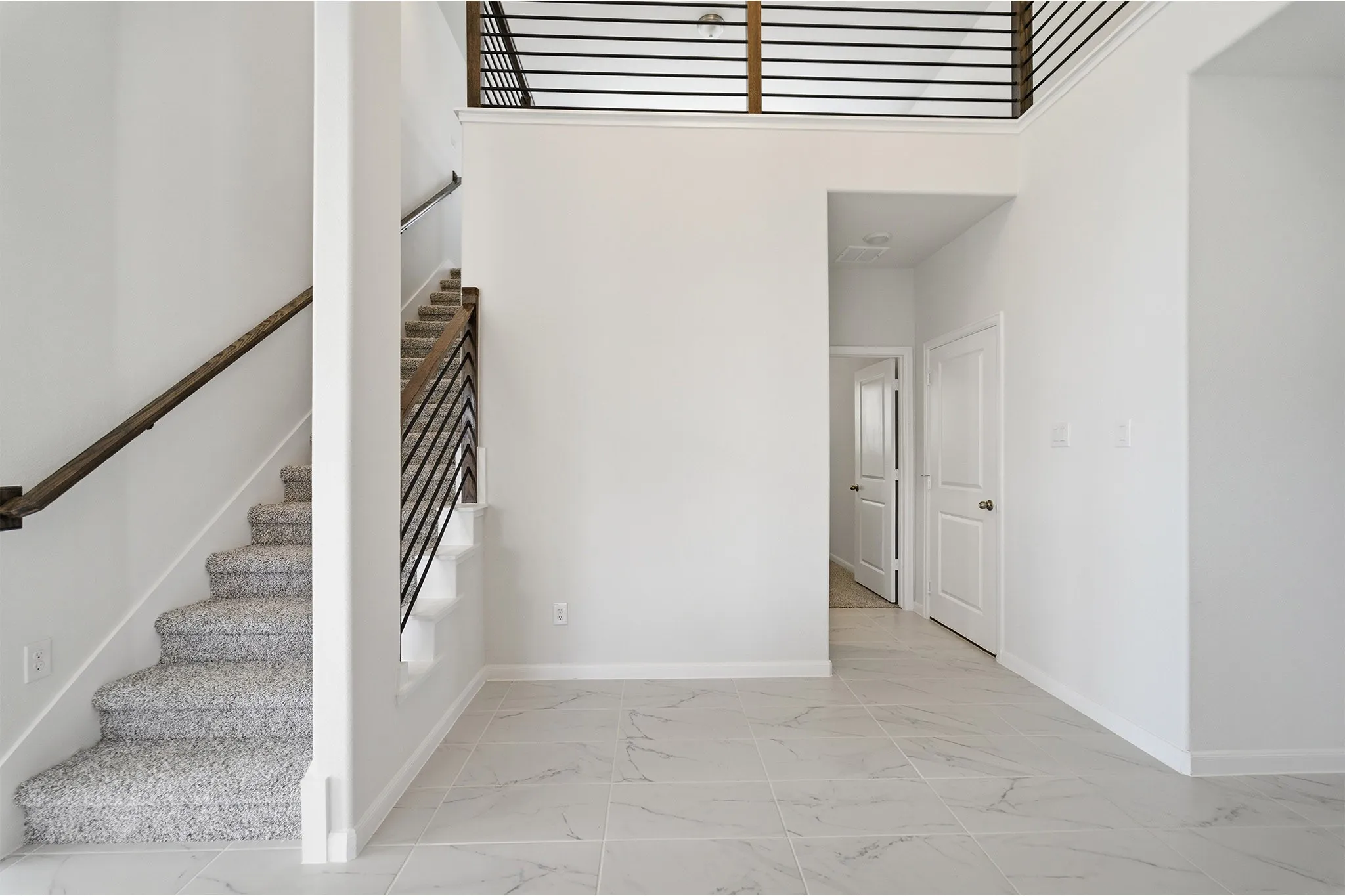 Two-story interior featuring a contemporary staircase with dark wood handrails and black metal balusters