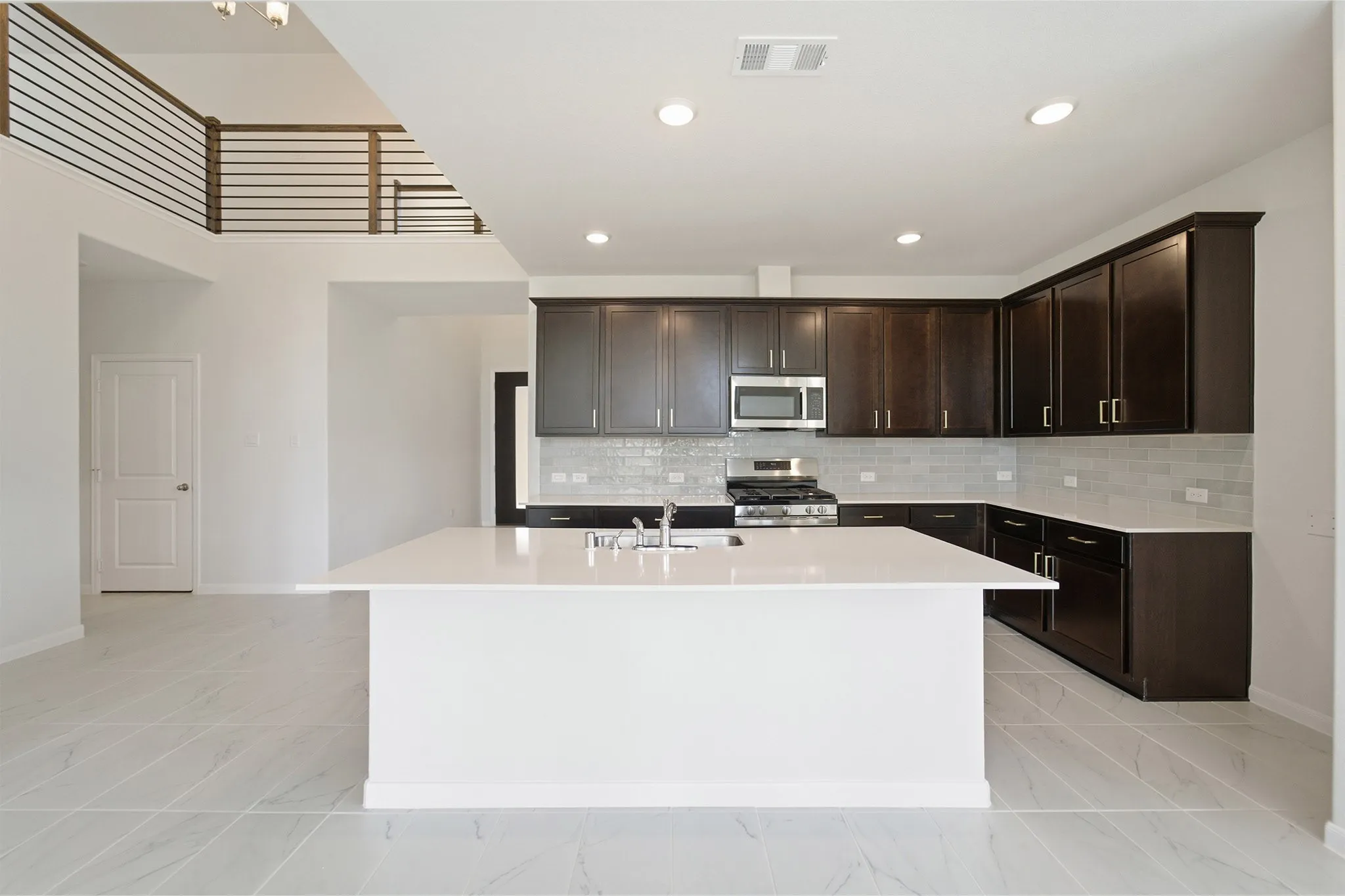 Open-concept kitchen with a large central island, dark wood-finish cabinetry, and stainless steel appliances