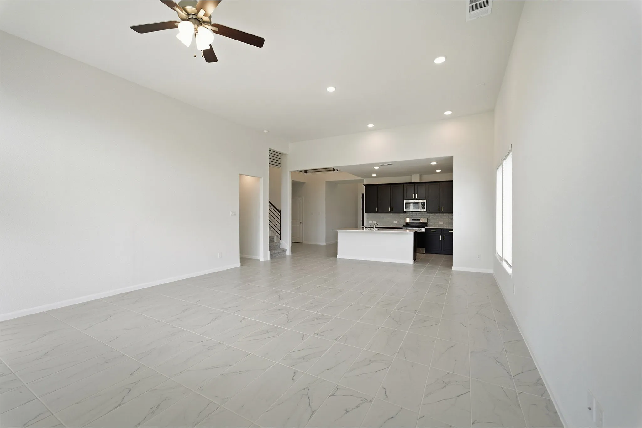 Open-concept living space featuring high ceilings, recessed lighting, and large format tile flooring