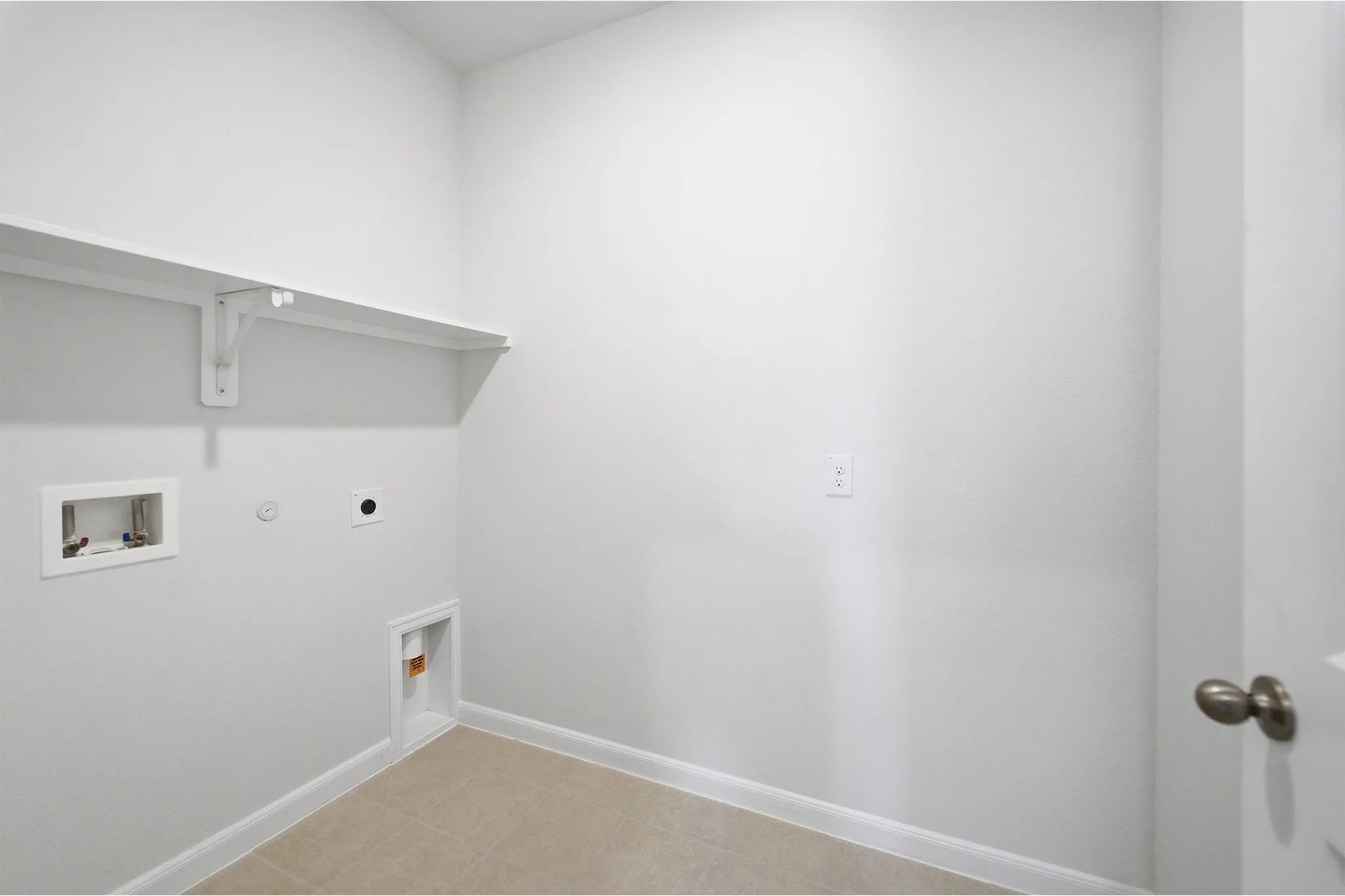 Utility space with light beige floor tile and white baseboards