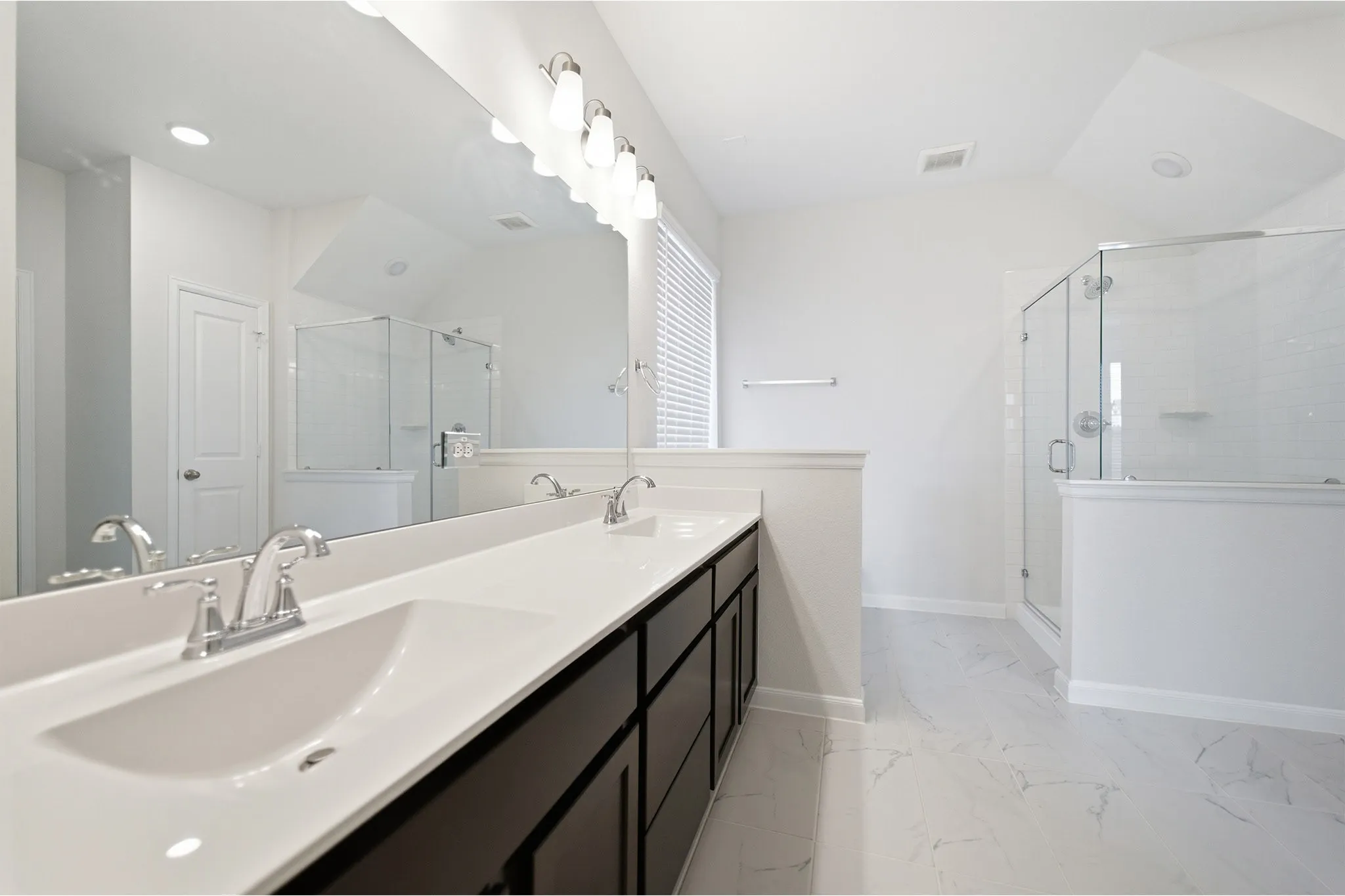 Dual sink vanity with dark wood-finish cabinetry, a white countertop, and chrome fixtures