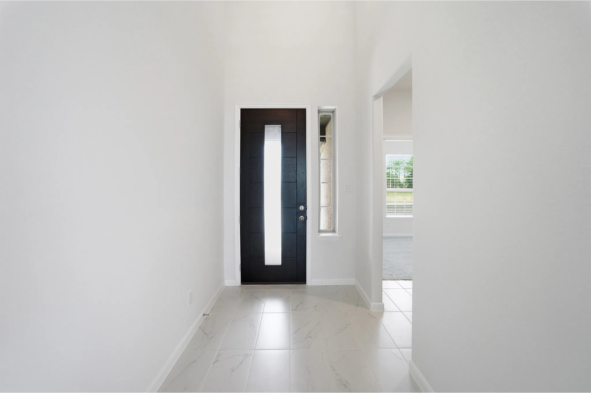 Entry foyer with vaulted ceilings, featuring a dark wood-finish door with frosted glass inset, an elongated sidelight, and light-toned tile flooring