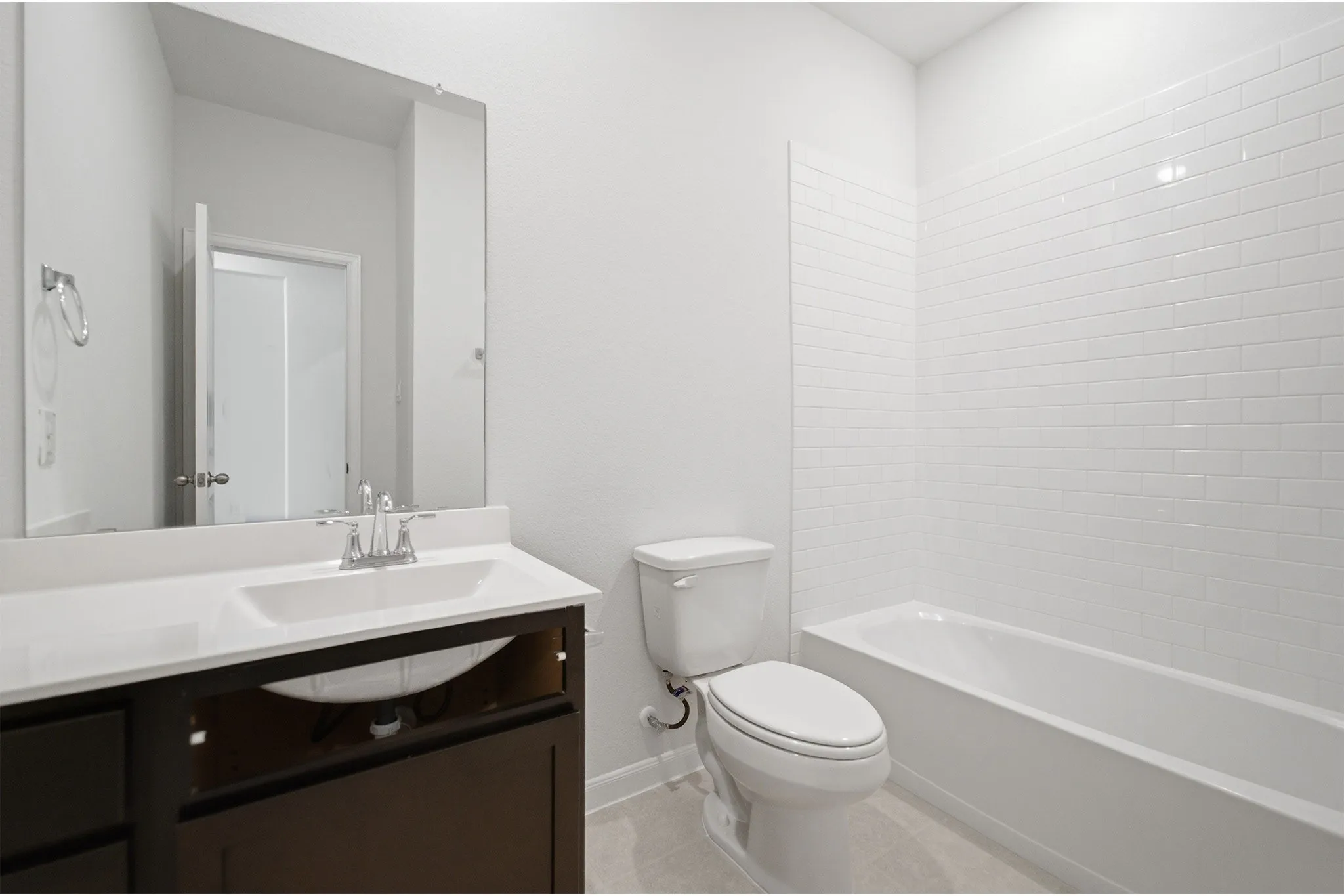 Bathroom featuring a dark wood-finish vanity with an integrated sink, polished chrome faucet, and a large wall-mounted mirror