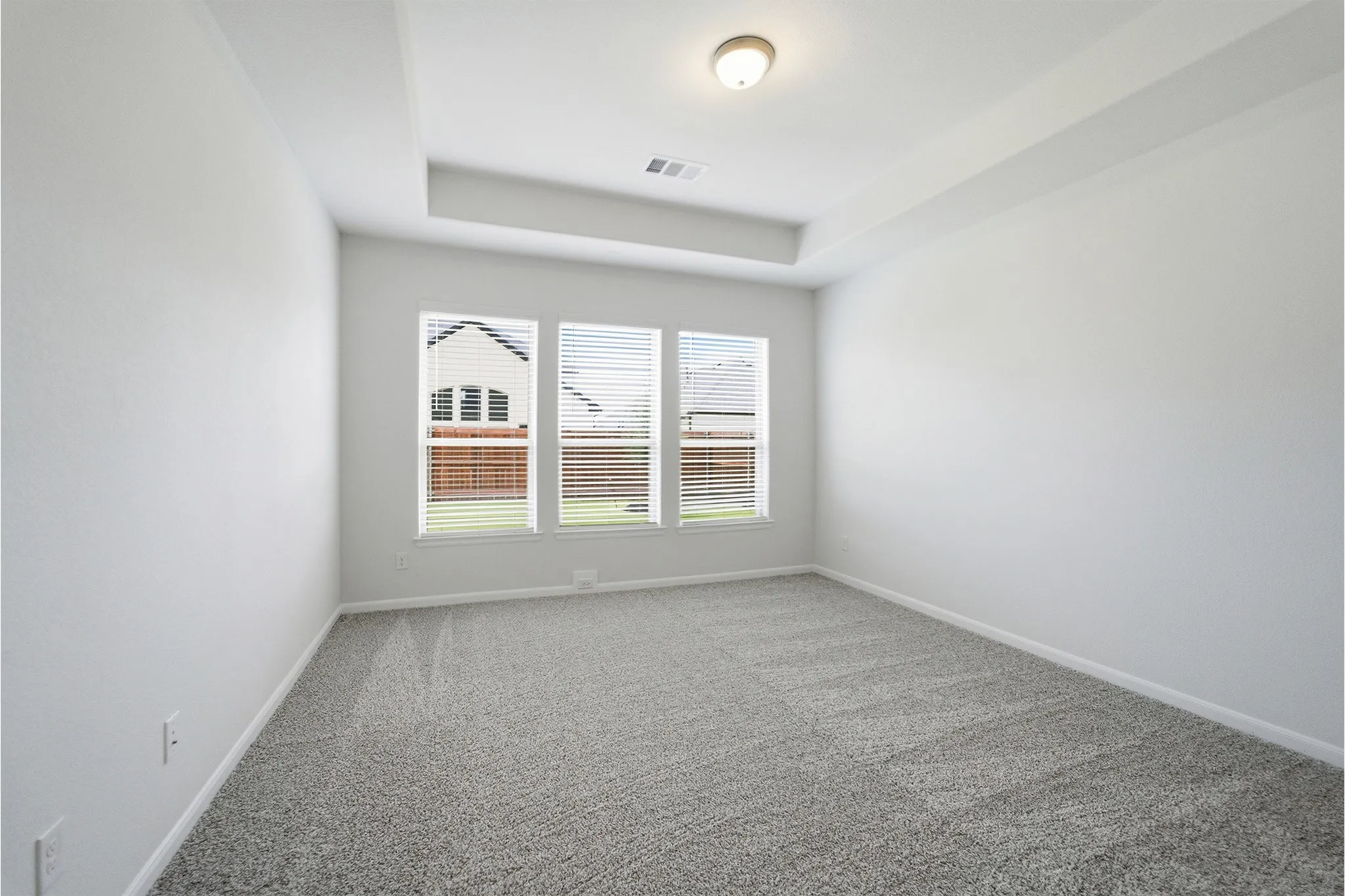 Spacious room featuring a tray ceiling, recessed lighting, and grey patterned carpeting