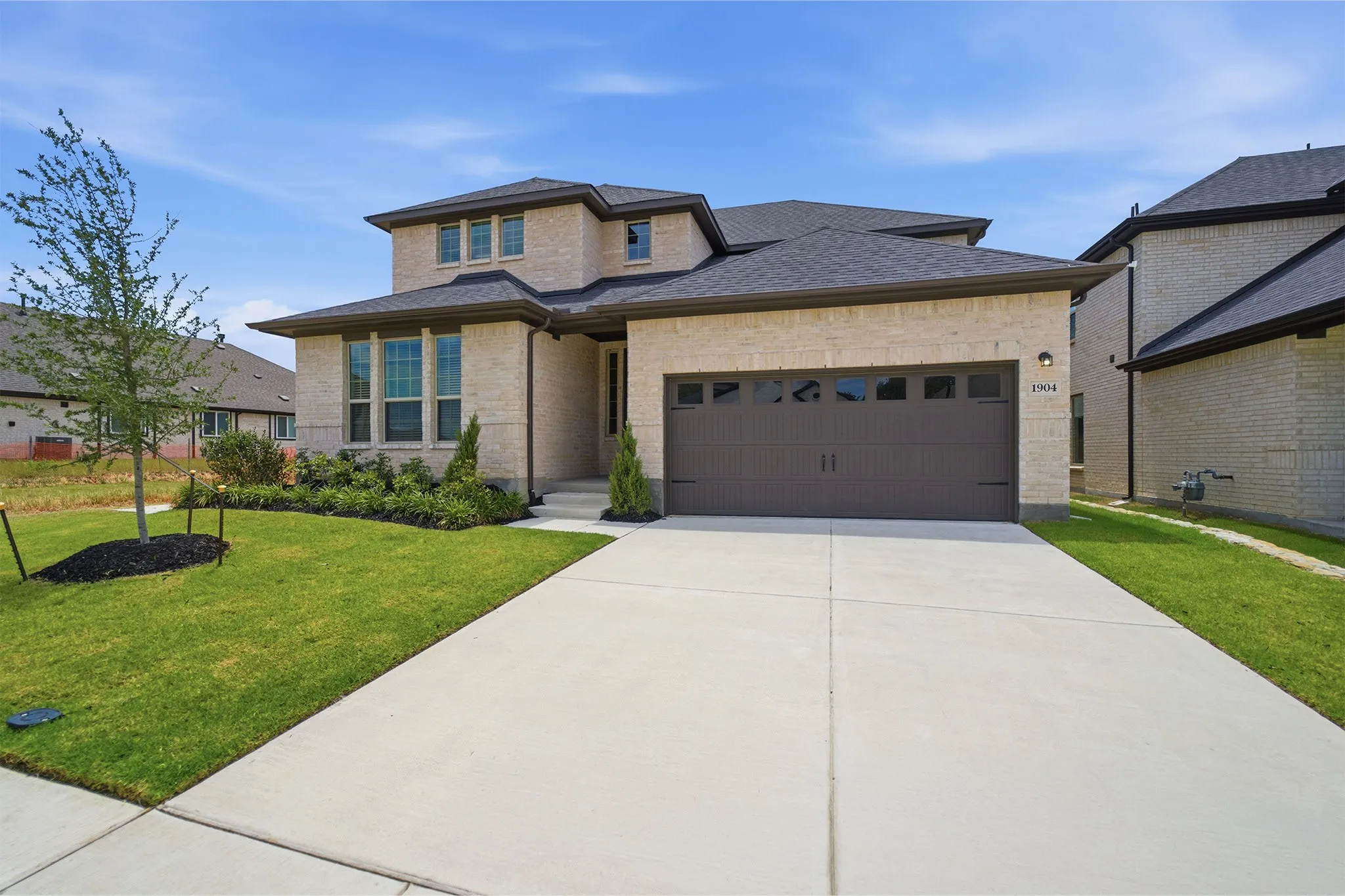 Contemporary two-story residence featuring light-colored brick masonry and a dark shingle roof