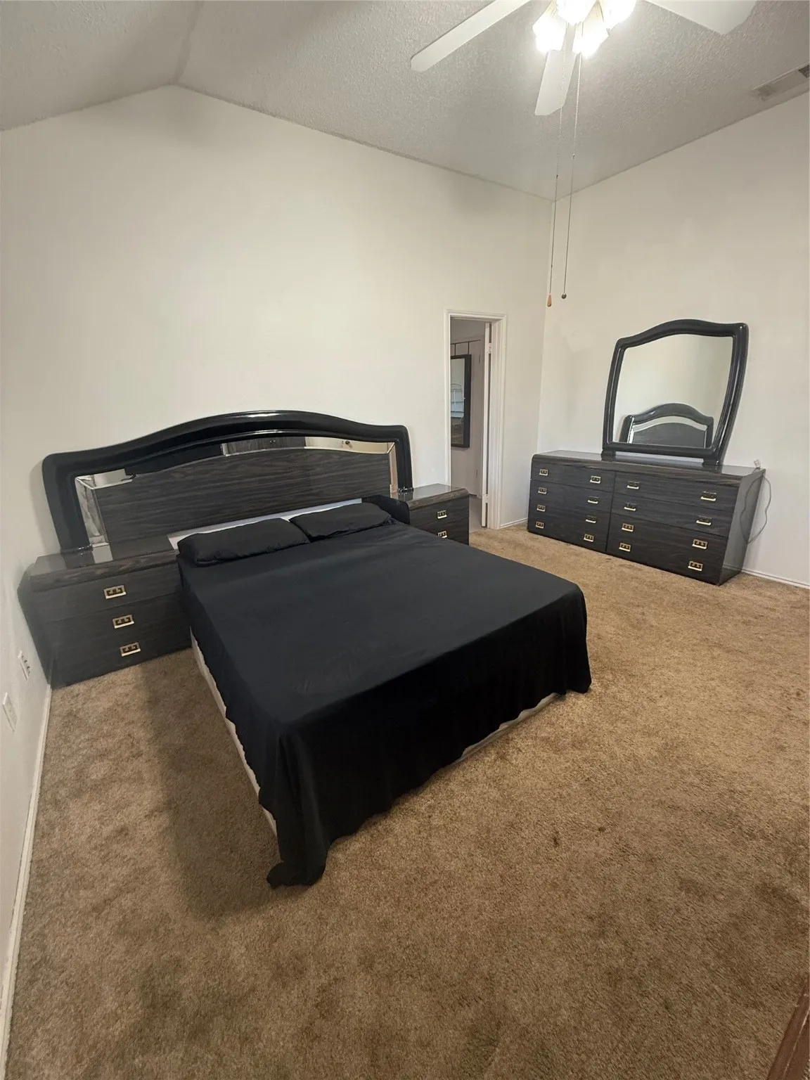 Bedroom featuring a textured ceiling, light colored carpet, a ceiling fan, and lofted ceiling