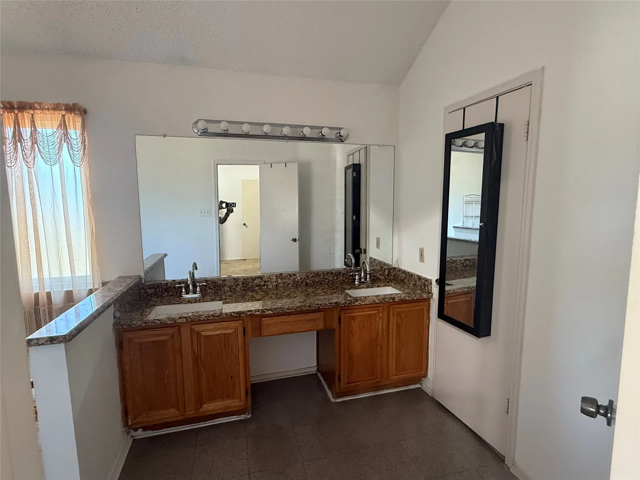 Full bathroom featuring double vanity, a textured ceiling, and lofted ceiling