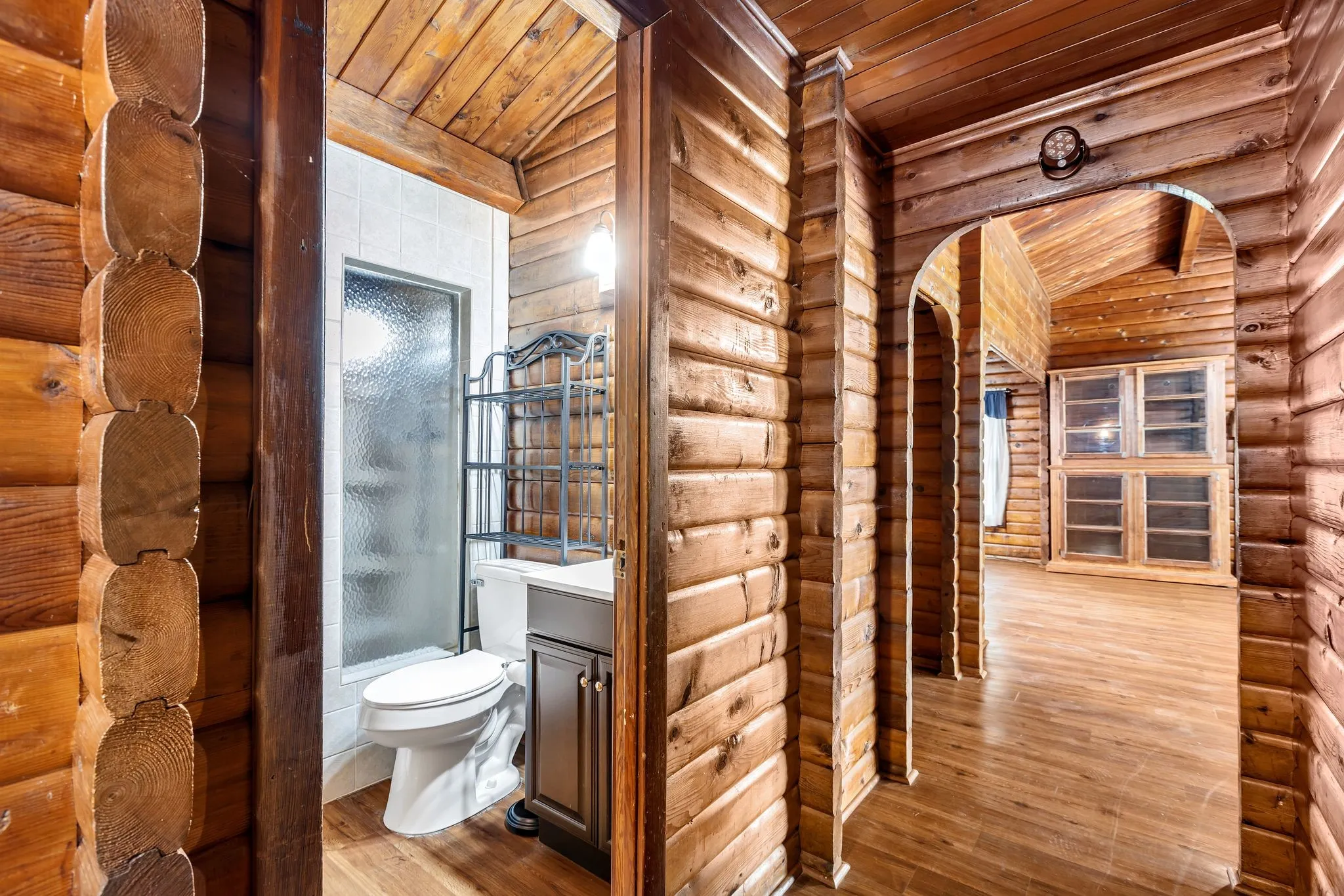 Full bath featuring vanity, hardwood / wood-style floors, rustic walls, wooden ceiling, and shower