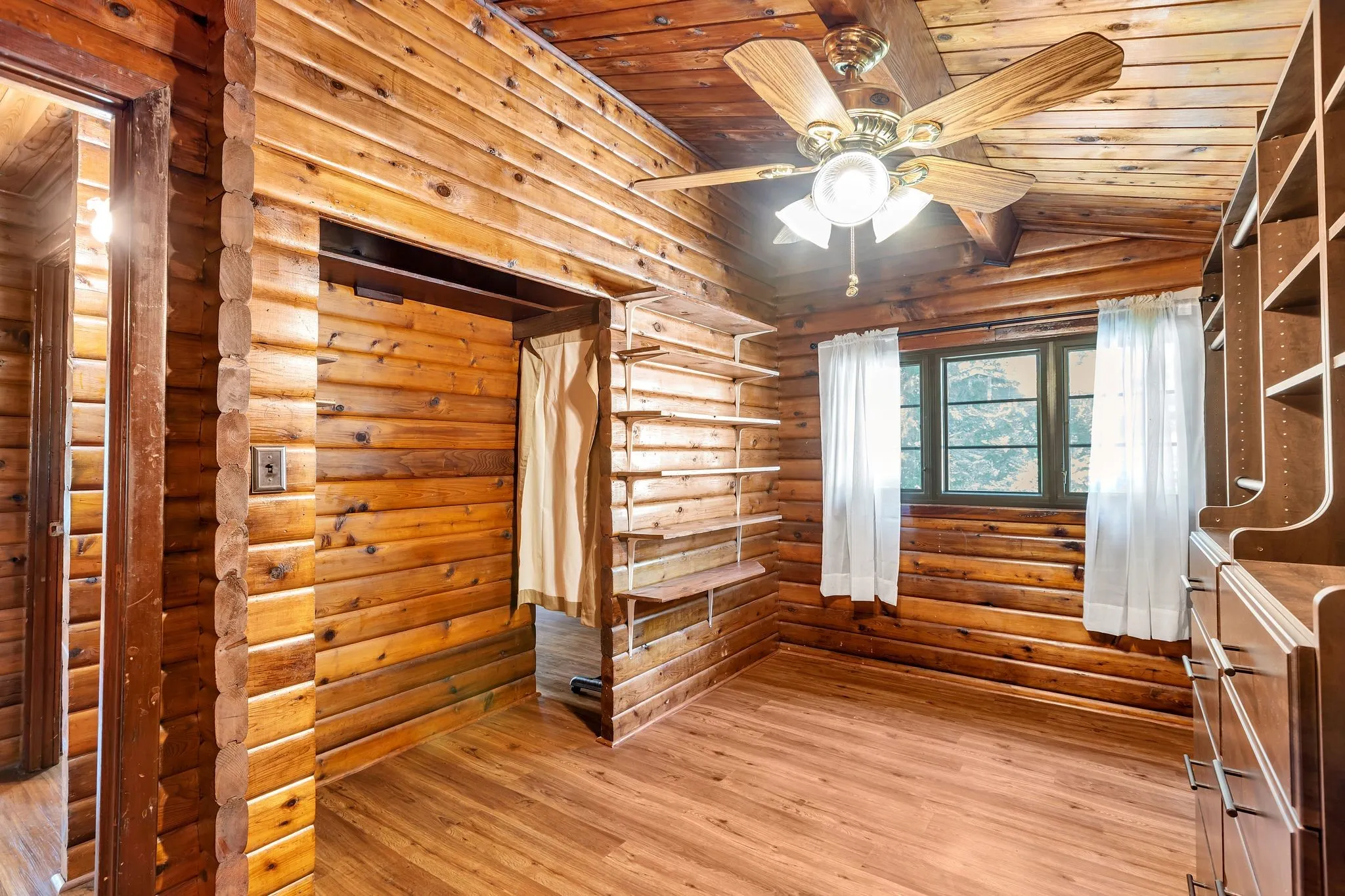 Closet with rustic walls, wood-type flooring, wood ceiling, a ceiling fan