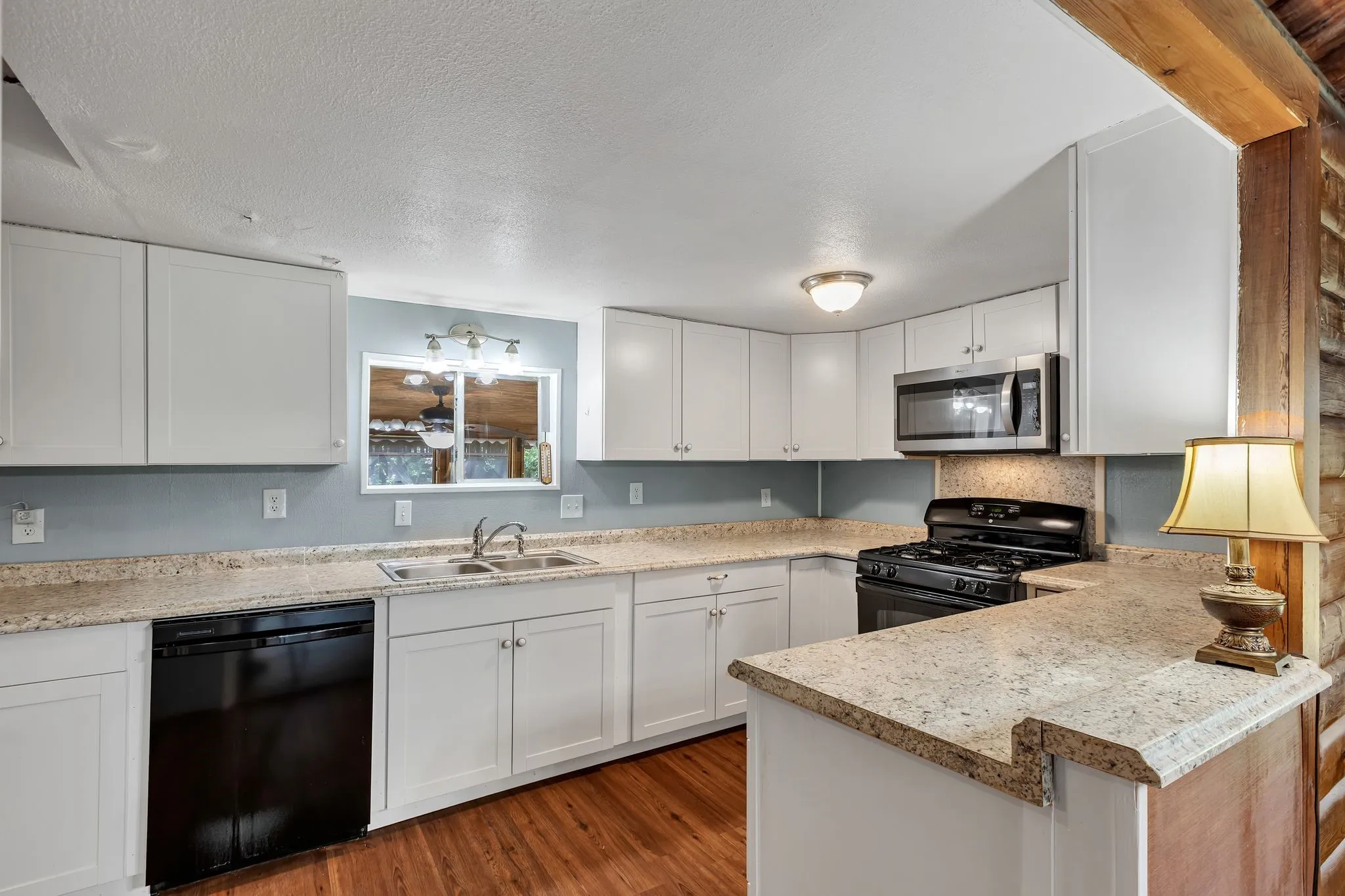 Kitchen featuring white cabinetry, black appliances, light countertops, dark wood finished floors