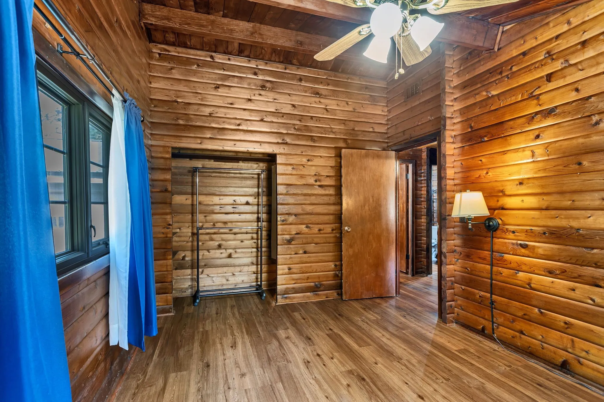 Bedroom with log walls, hardwood / wood-style floors, and wood ceiling