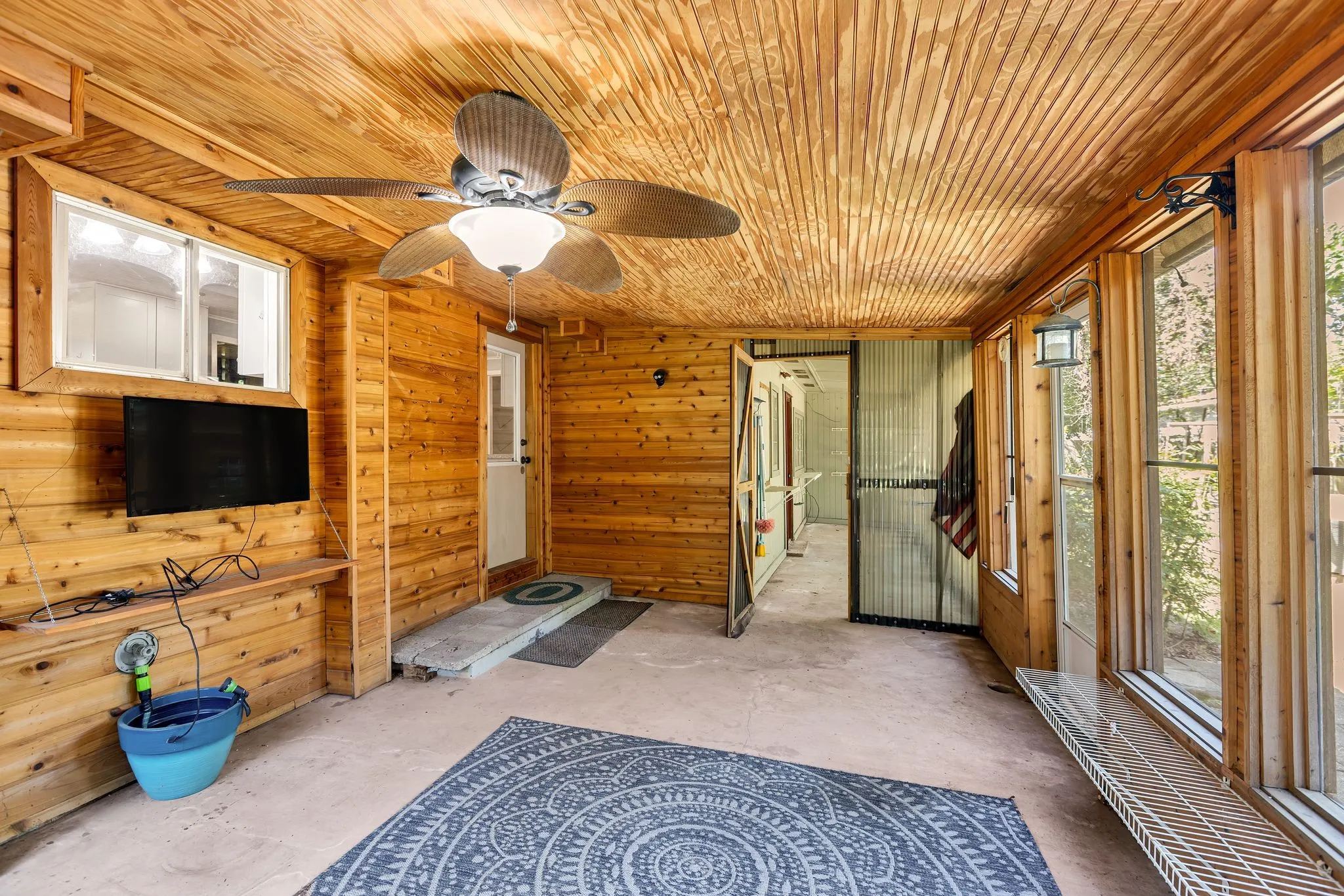 Sunroom featuring heating unit, roll up shades with screens and a ceiling fan