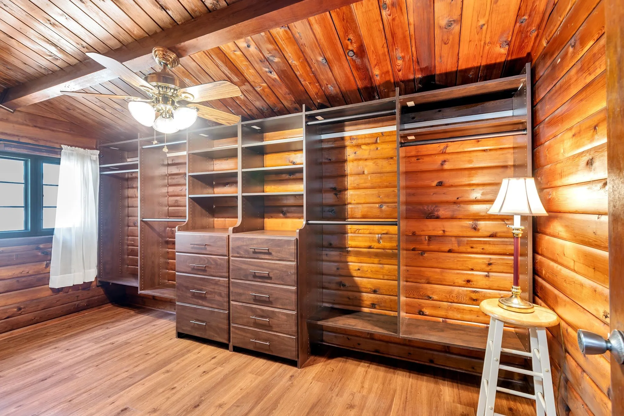 Spacious closet featuring a ceiling fan, light wood-type flooring, and beamed ceiling