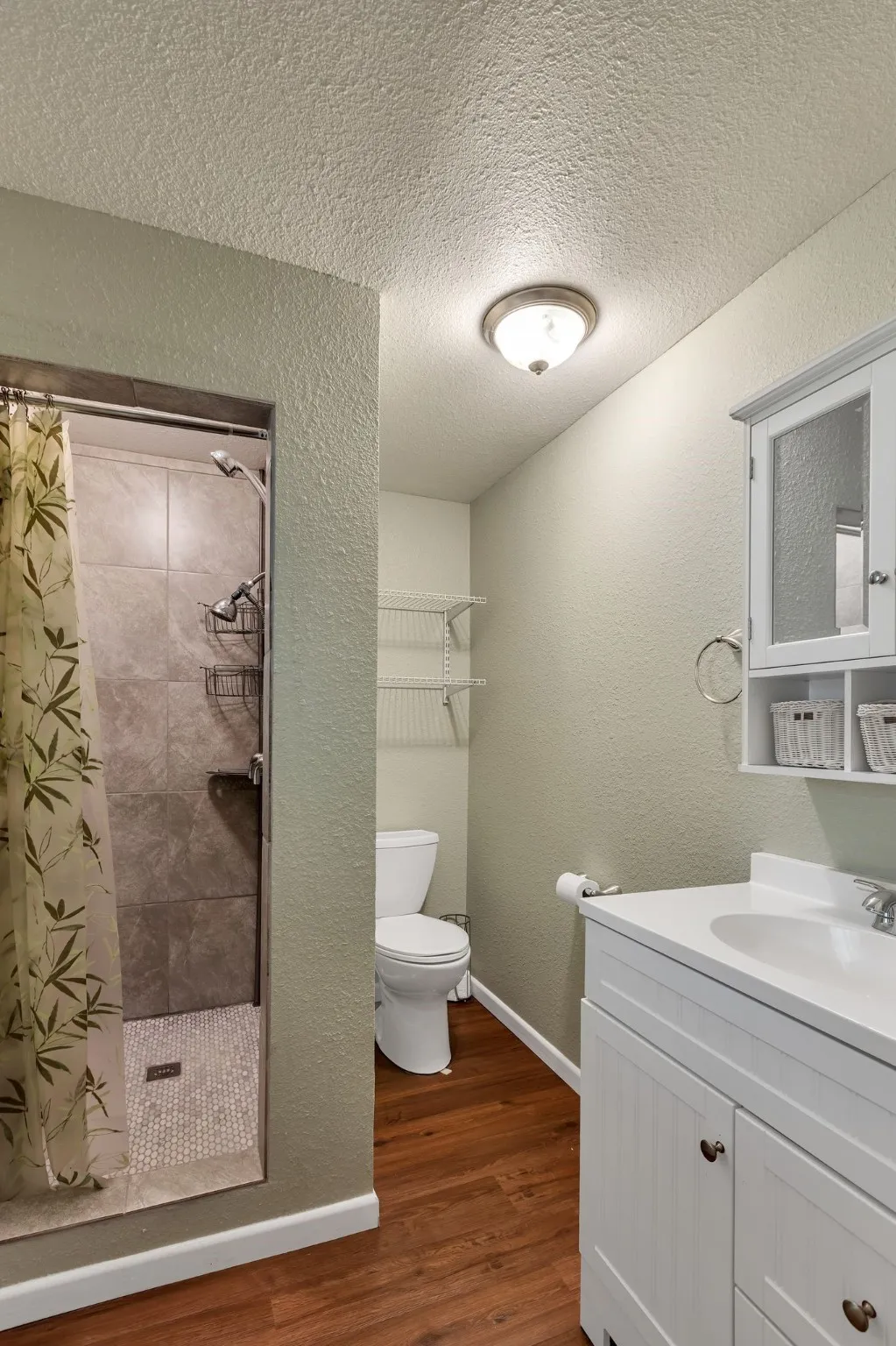 Bathroom featuring a shower stall, vanity, dark wood finished floors