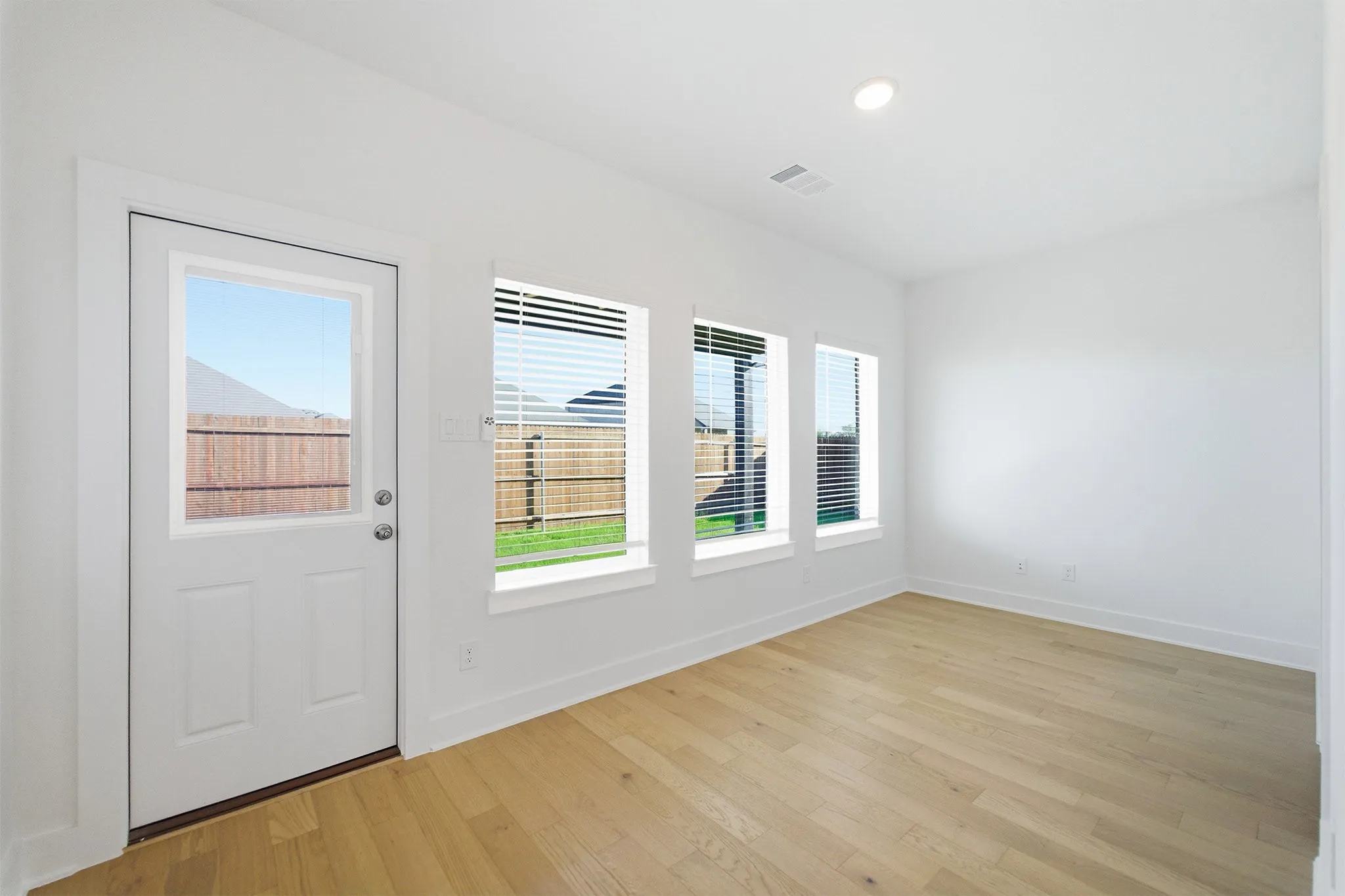 Bright interior space featuring light wood-finish flooring, white walls, and a recessed ceiling light