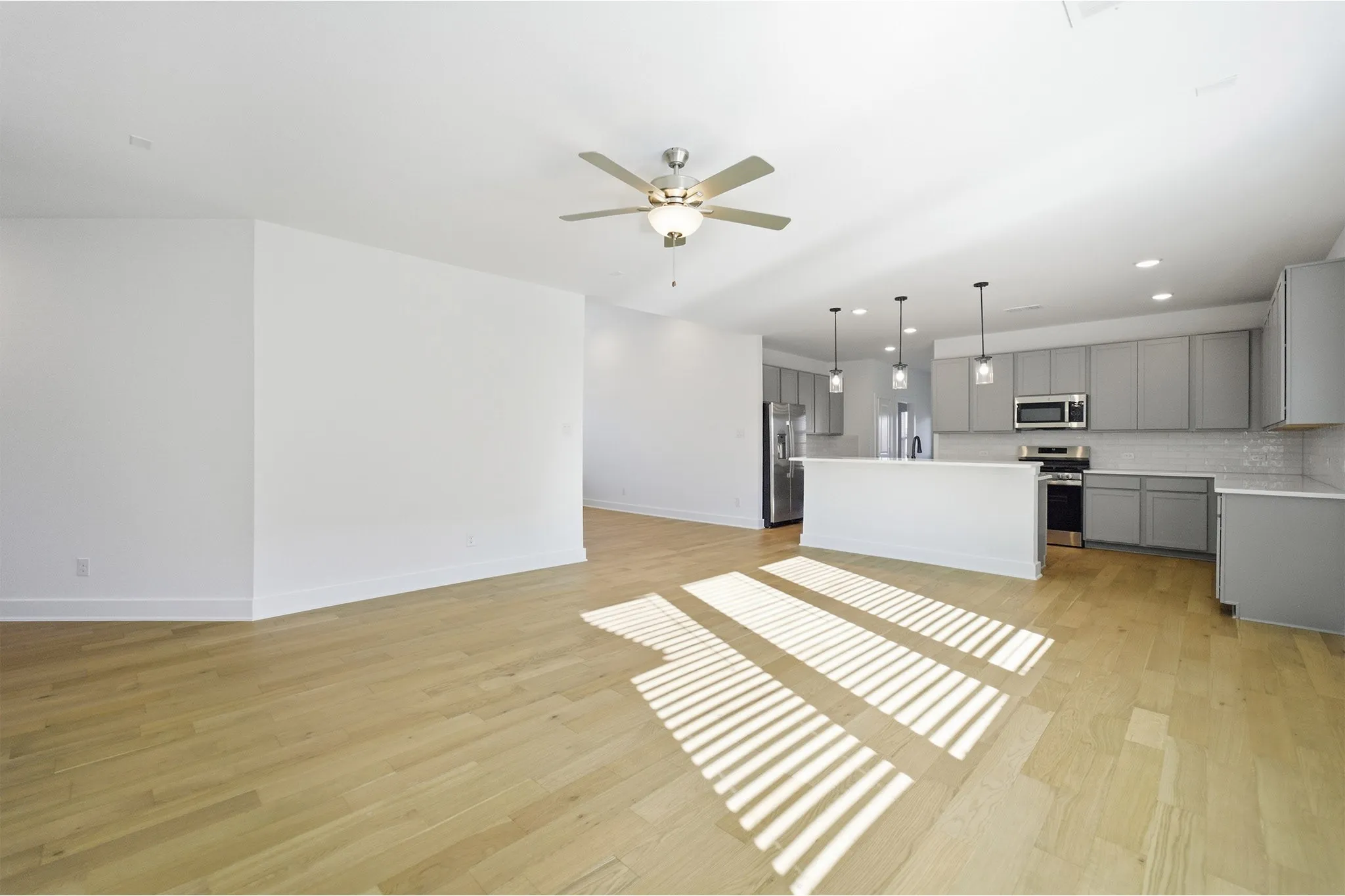 Open-concept living space with wood-finish flooring, a contemporary ceiling fan, and recessed lighting