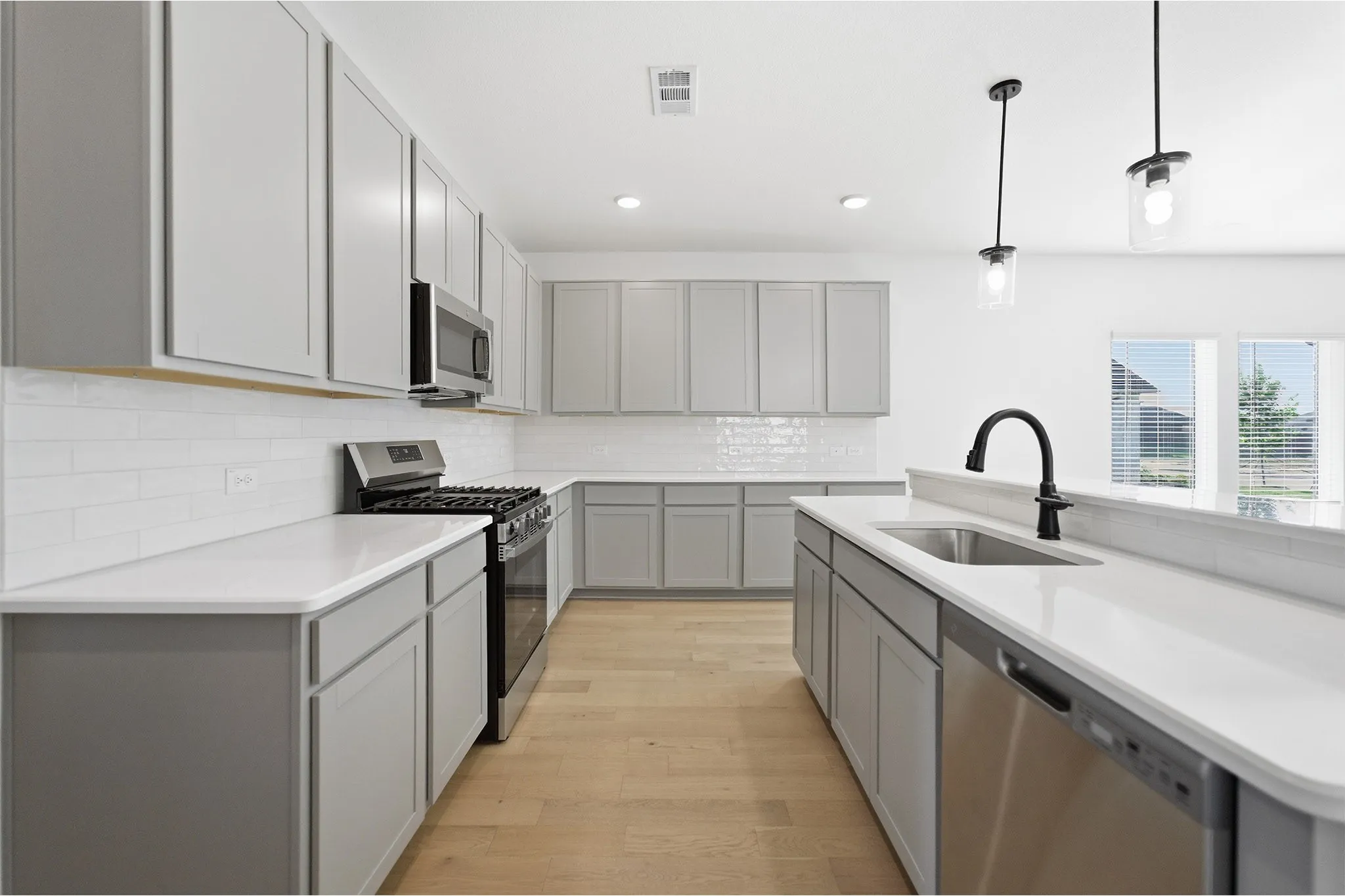 Modern kitchen featuring light gray cabinetry, white countertops, a subway tile backsplash, and wood-finish flooring