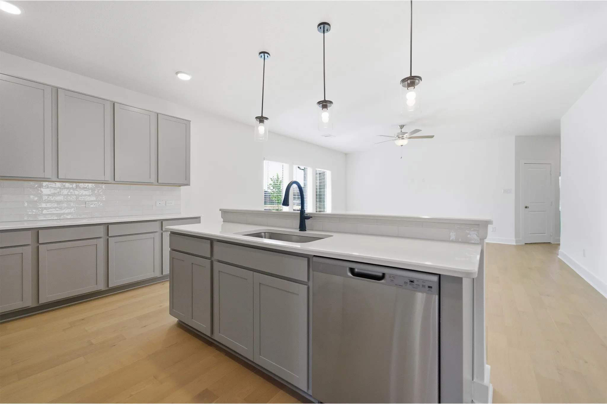 Kitchen island featuring an undermount sink, a gooseneck faucet, and a stainless steel dishwasher