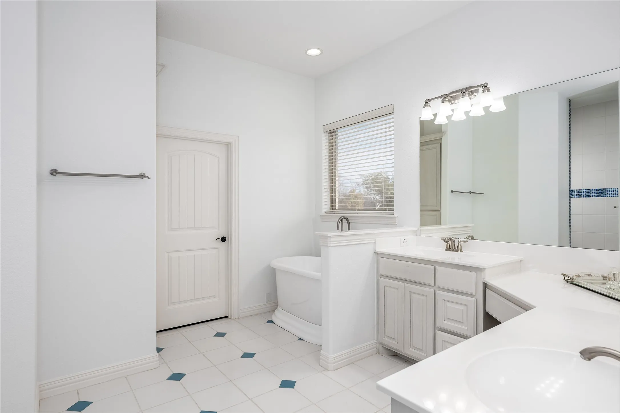 Master Bathroom with two vanities, a freestanding tub, light tile patterned flooring, and recessed lighting