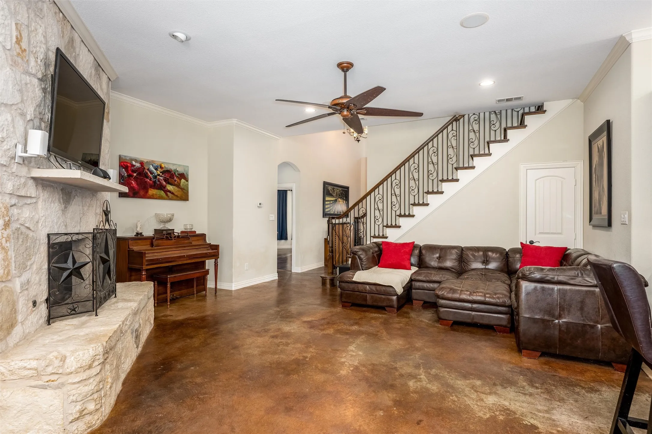 Living room with ornamental molding, concrete flooring, stairway, a fireplace, and arched walkways