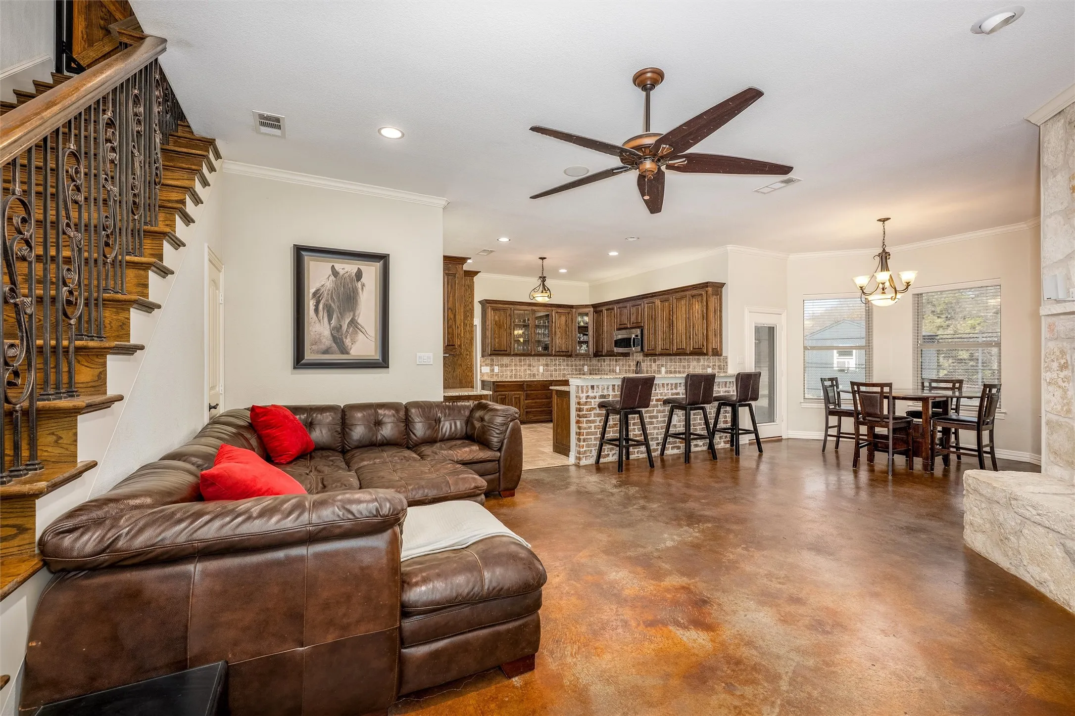 Living room featuring surround sound speakers, concrete floors, ceiling fan, a chandelier, crown molding, and recessed lighting