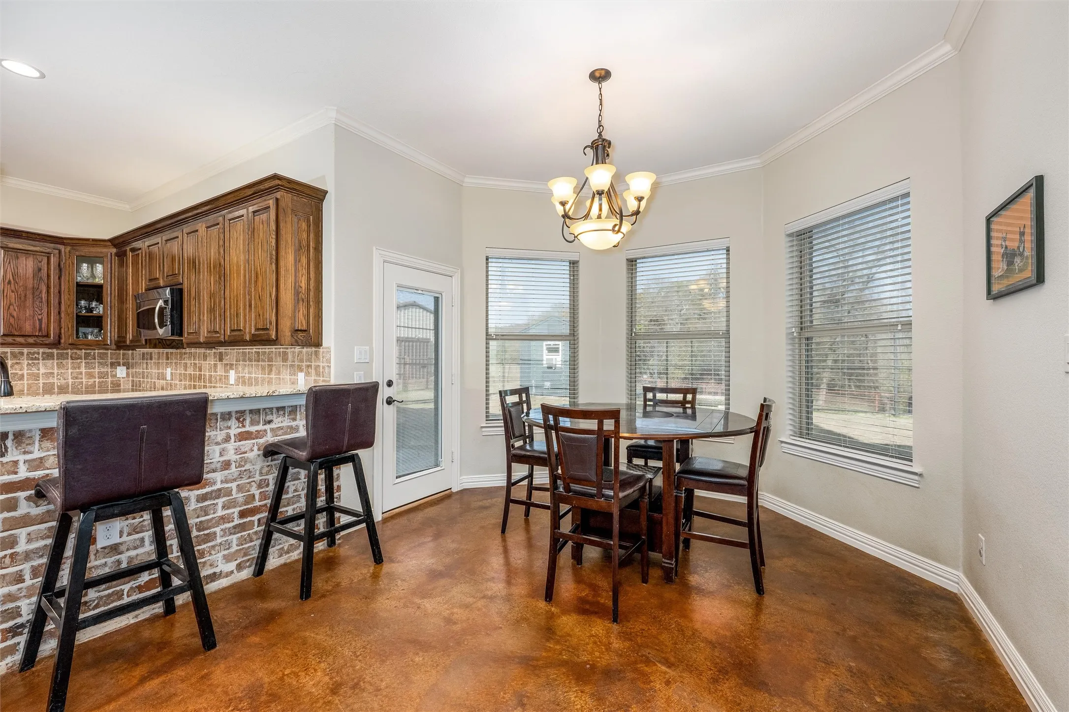 Dining area with finished concrete flooring, crown molding, and a chandelier