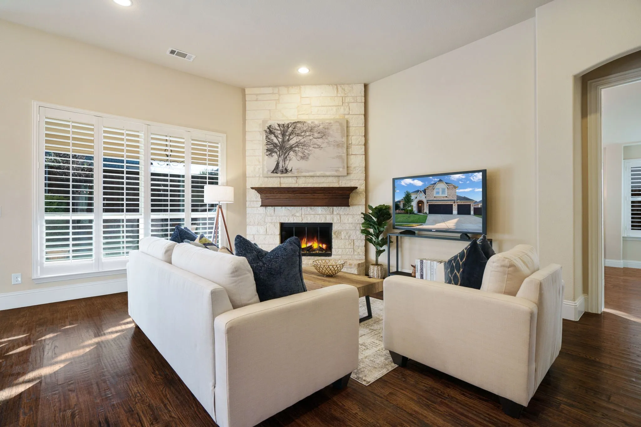 Bright and inviting family room featuring a stone fireplace, large windows, and seamless access to the backyard.